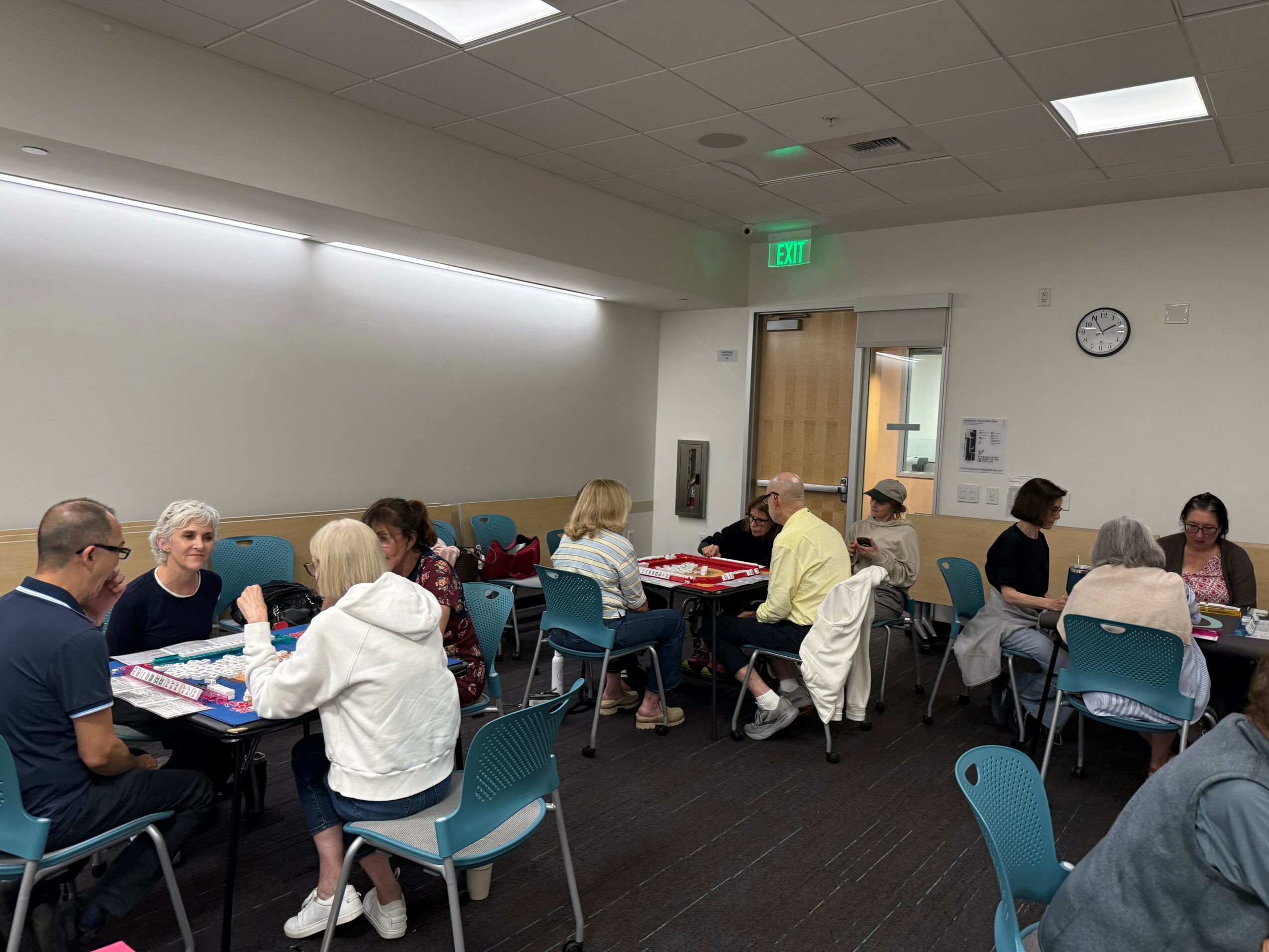 Group of people sitting at tables in a room, engaging in activities or conversations.