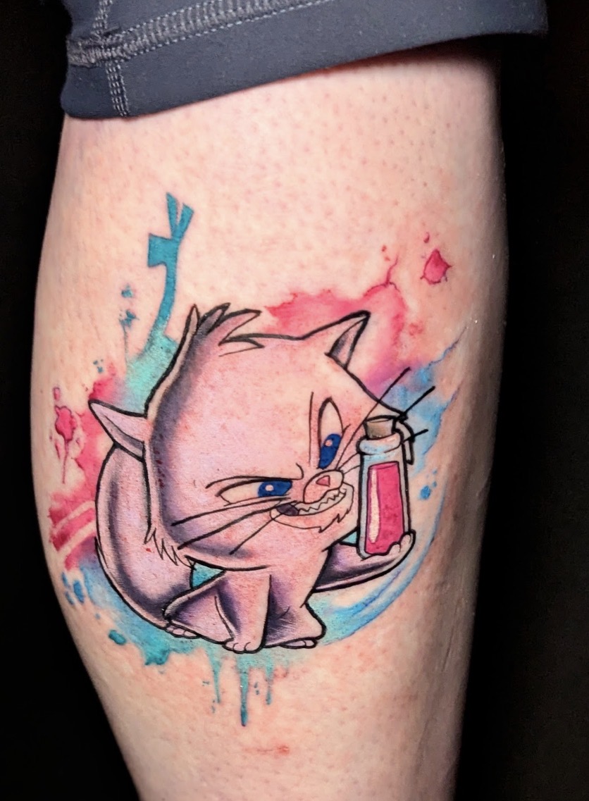 Tattoo of a sad cartoon cat with a tear and a thermometer, surrounded by colorful splashes.