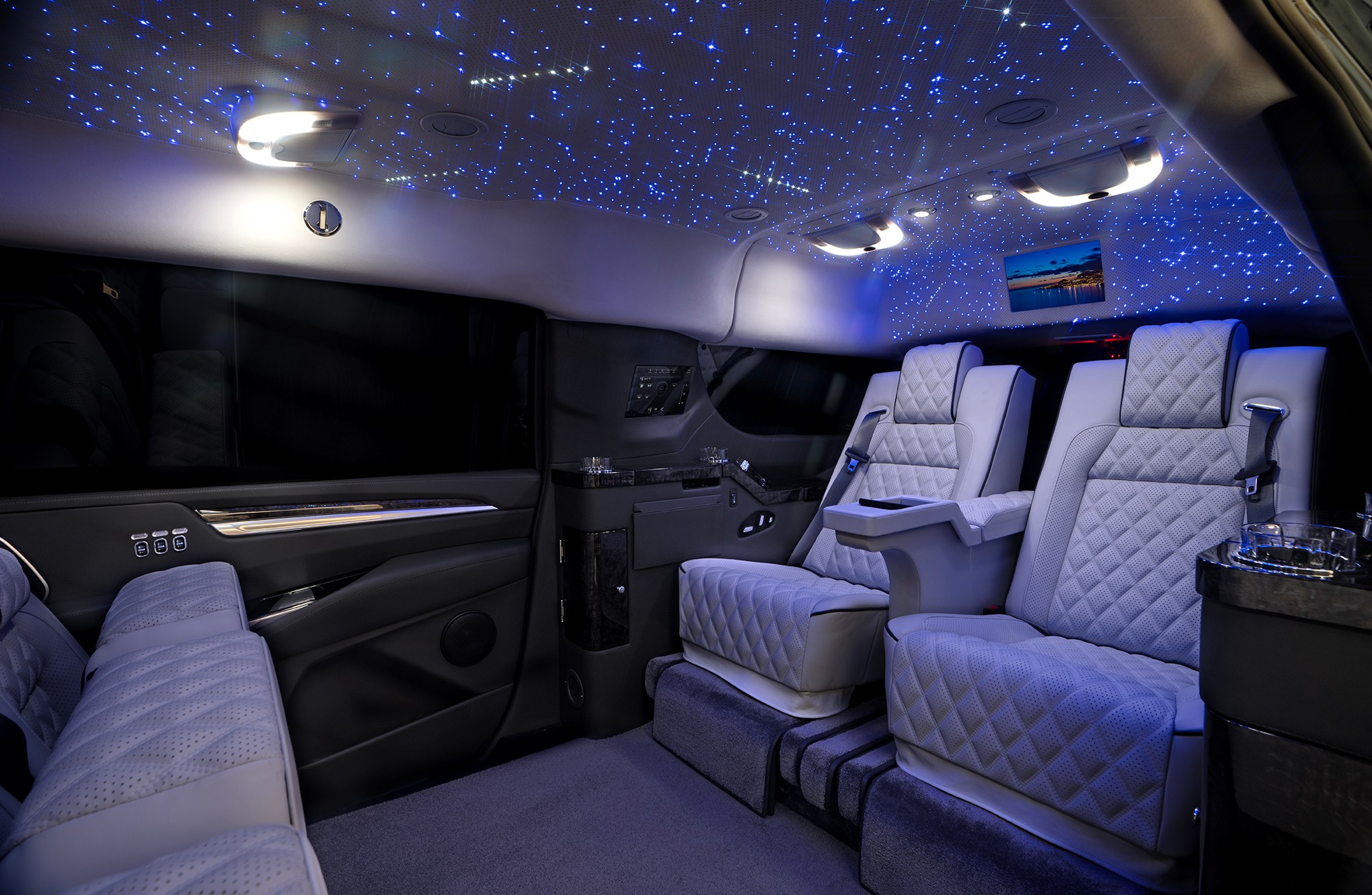 Luxury vehicle interior with starry ceiling, plush seats, and ambient lighting.