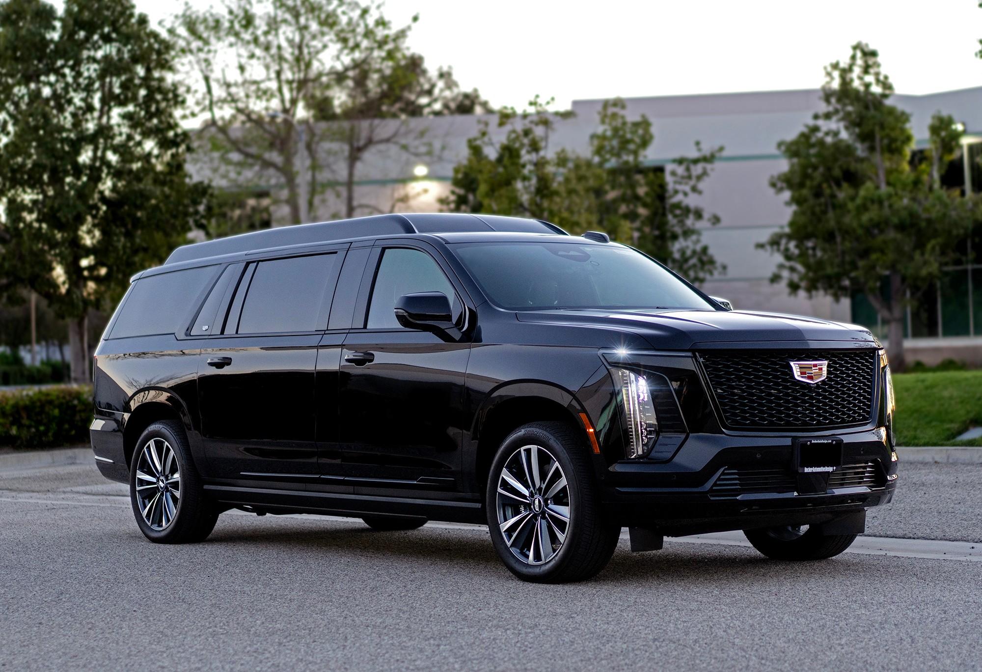 Black SUV parked on street with trees and building in background.