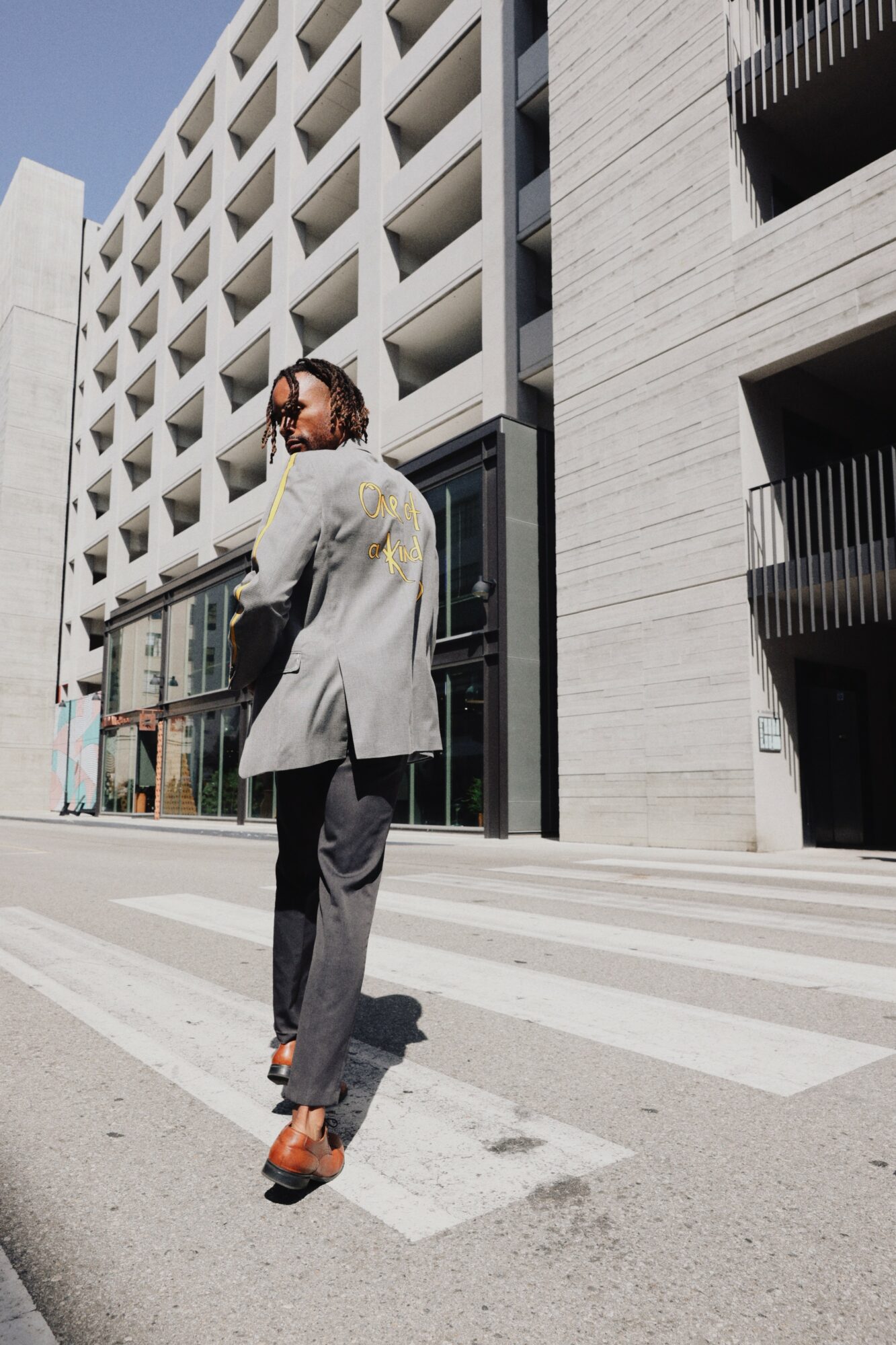 Person walking on crosswalk in urban area with modern building in background.