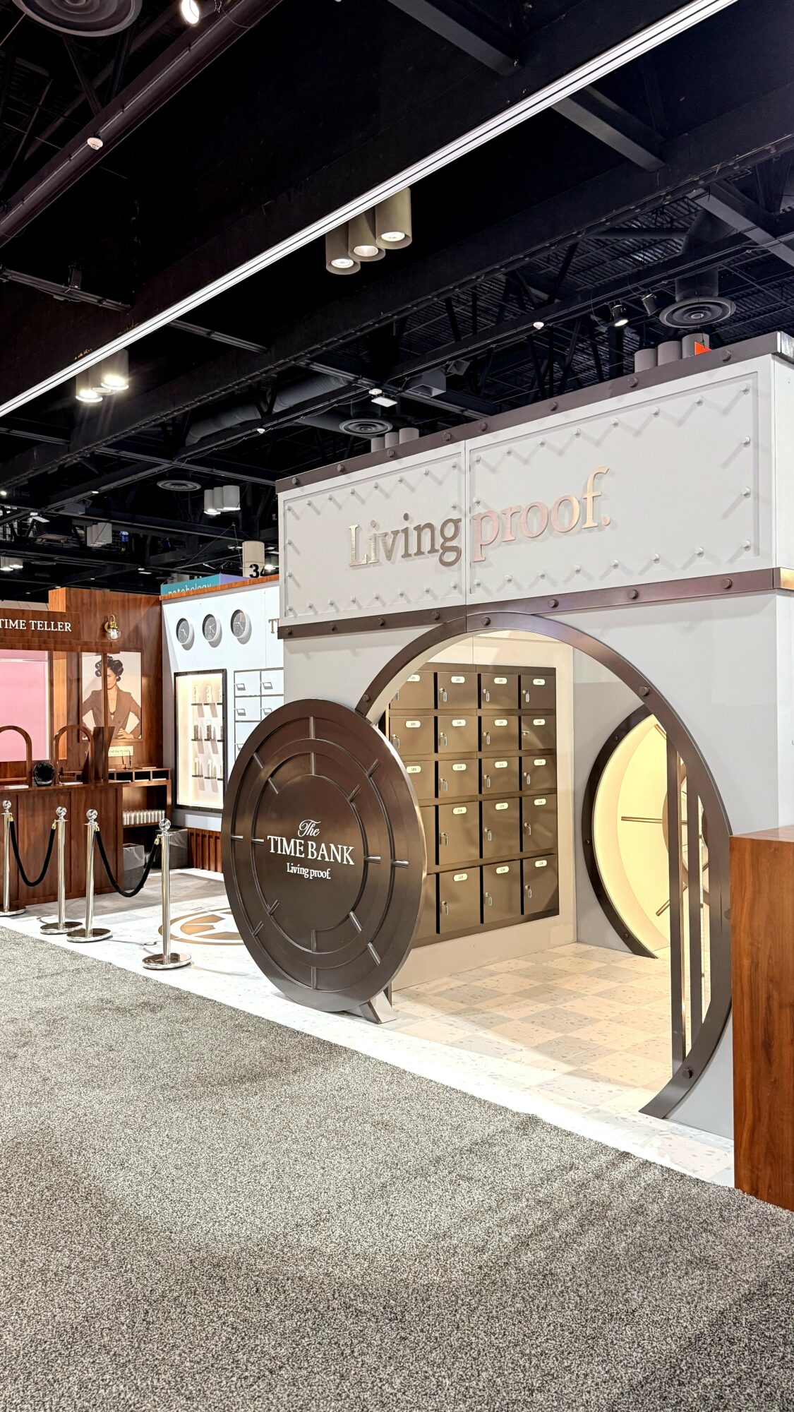 Booth with circular door and lockers, sign reads Living Room, part of an indoor exhibition space.