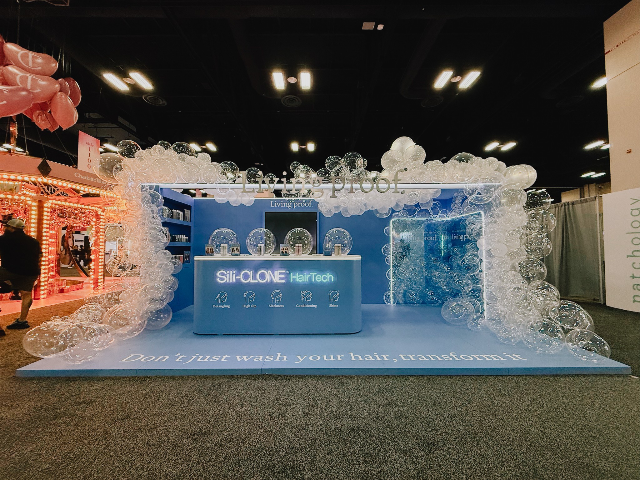 Booth with blue and white branding, surrounded by foam bubbles, at an indoor event or trade show.