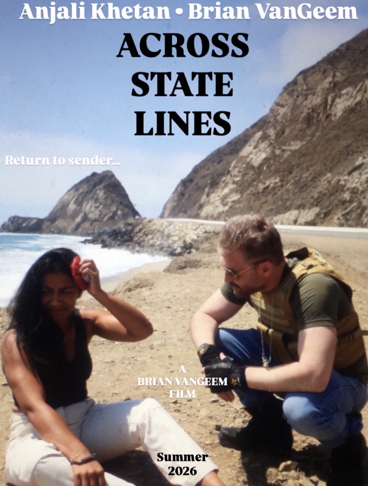 Two people sitting on a beach with rocky cliffs in the background, one adjusting sunglasses, the other looking down.