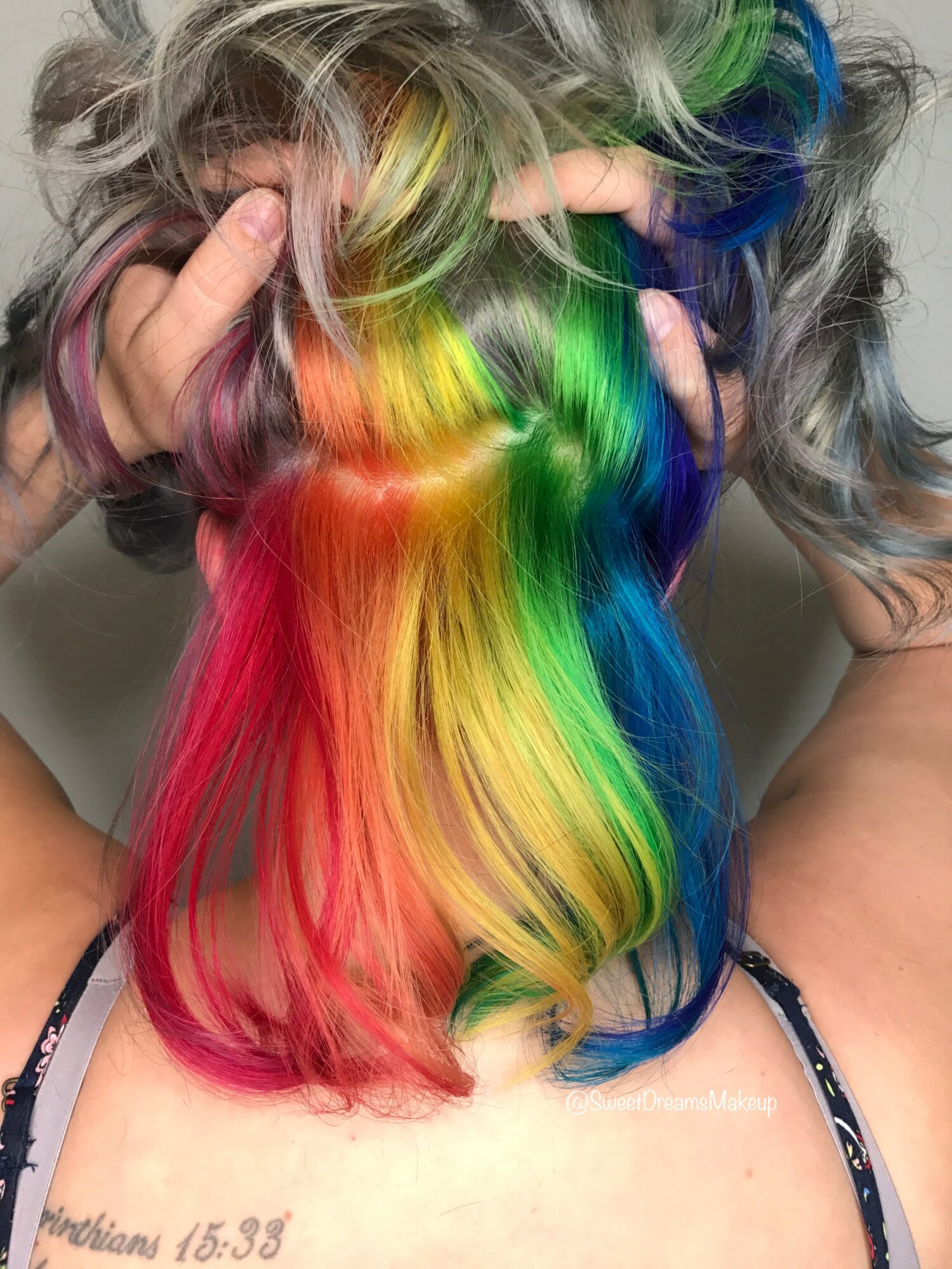 Person with long, multicolored rainbow hair covering face, showing vibrant colors and wavy texture.