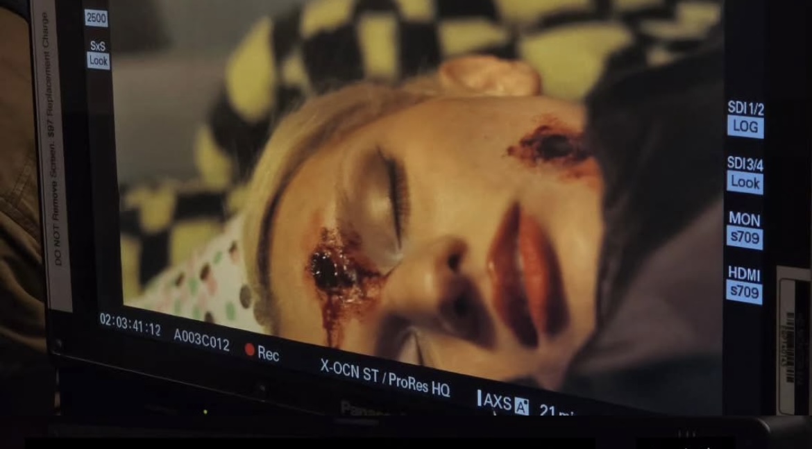 Close-up of a person's face with injuries and blood, lying still with eyes closed.
