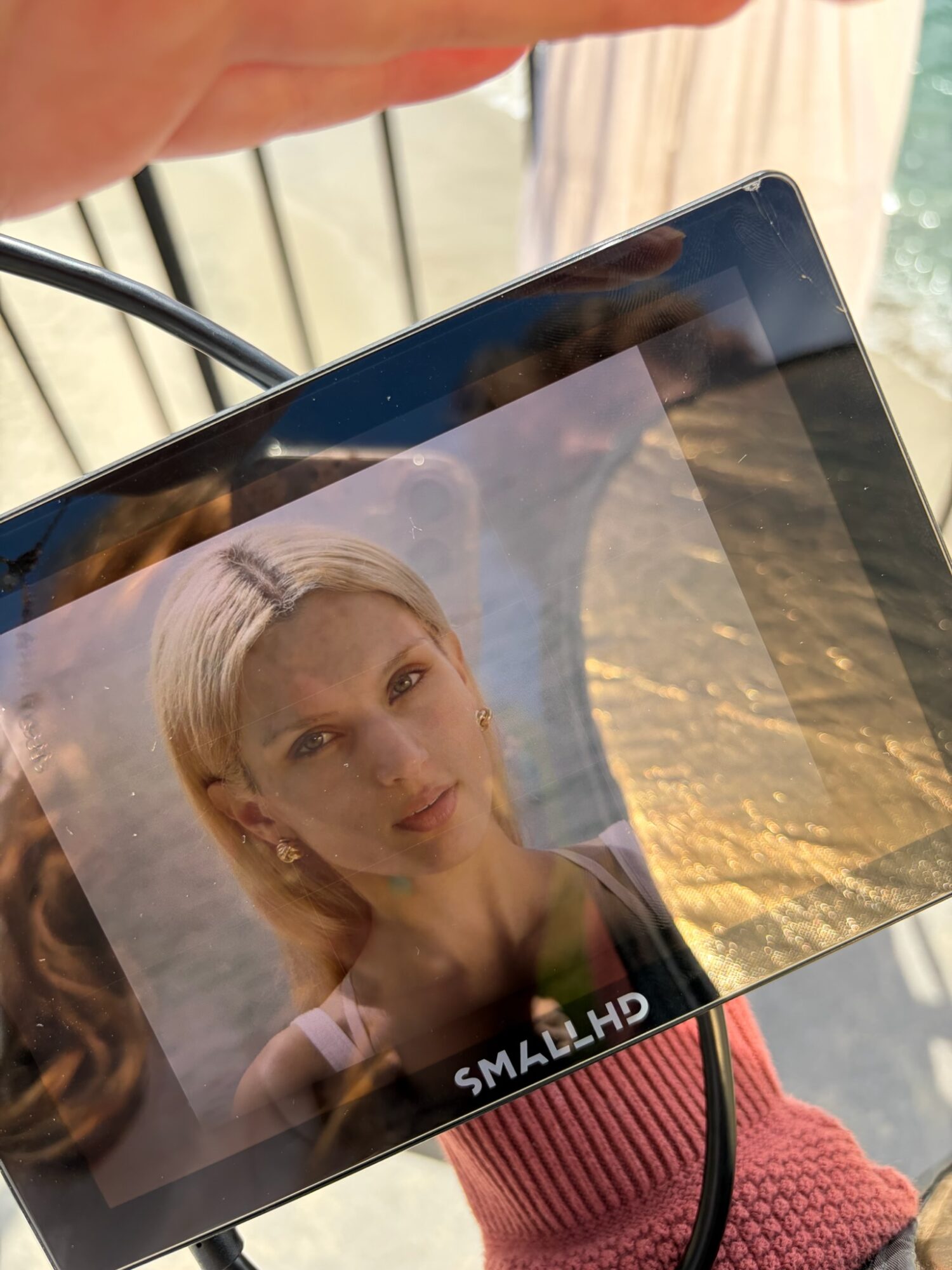 Tablet displaying a portrait of a woman with short blonde hair, outdoors with a sunset background.