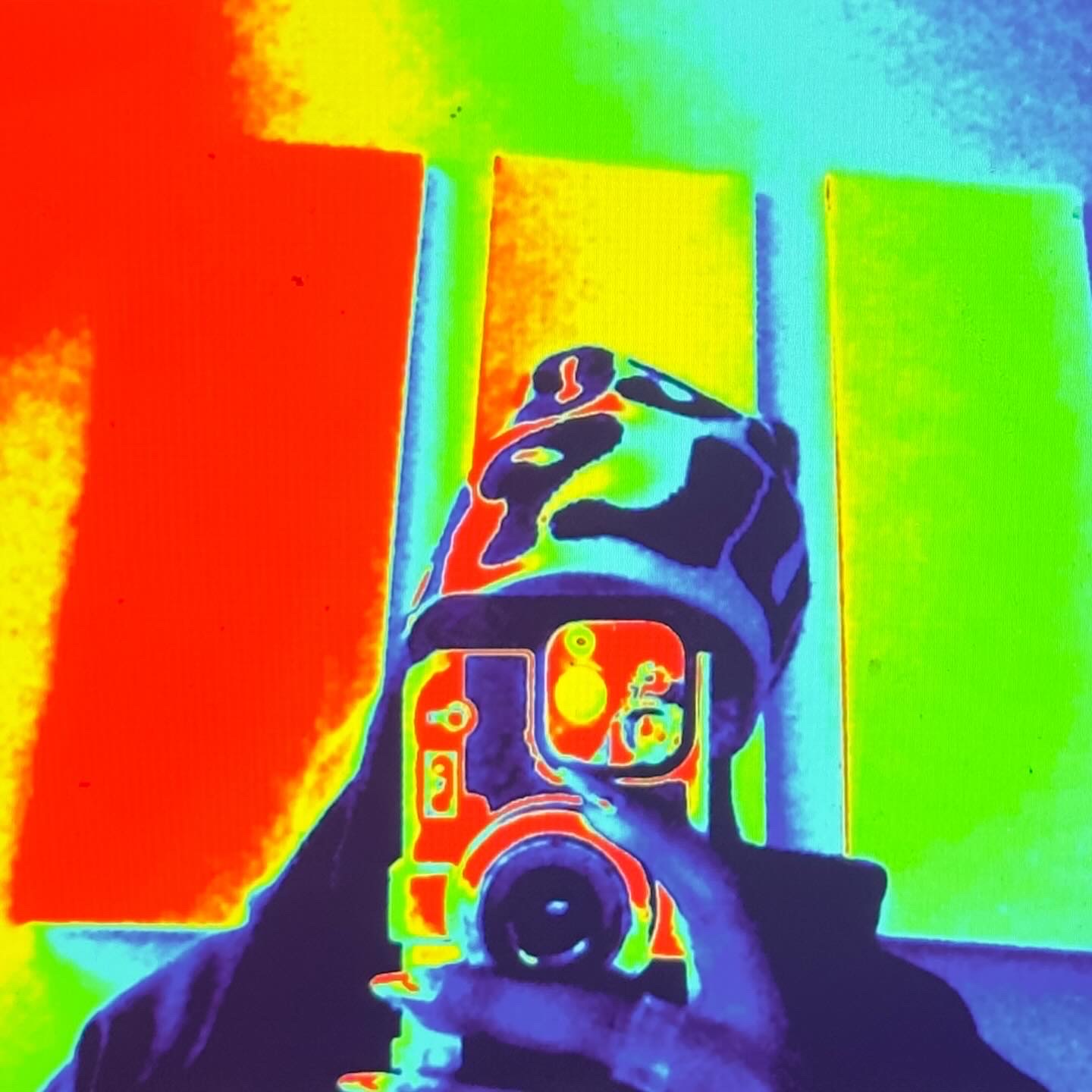 Person taking a photo with a colorful phone case, reflected in a mirror, with vibrant background colors.