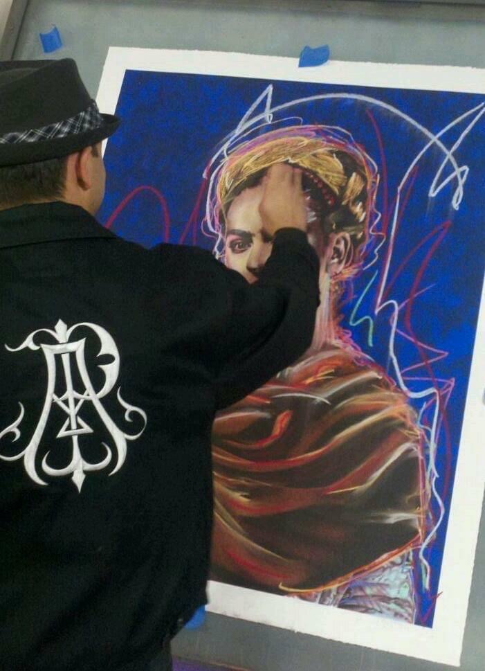 Artist working on a colorful portrait of a woman with a headscarf, using bright lines and vibrant colors.