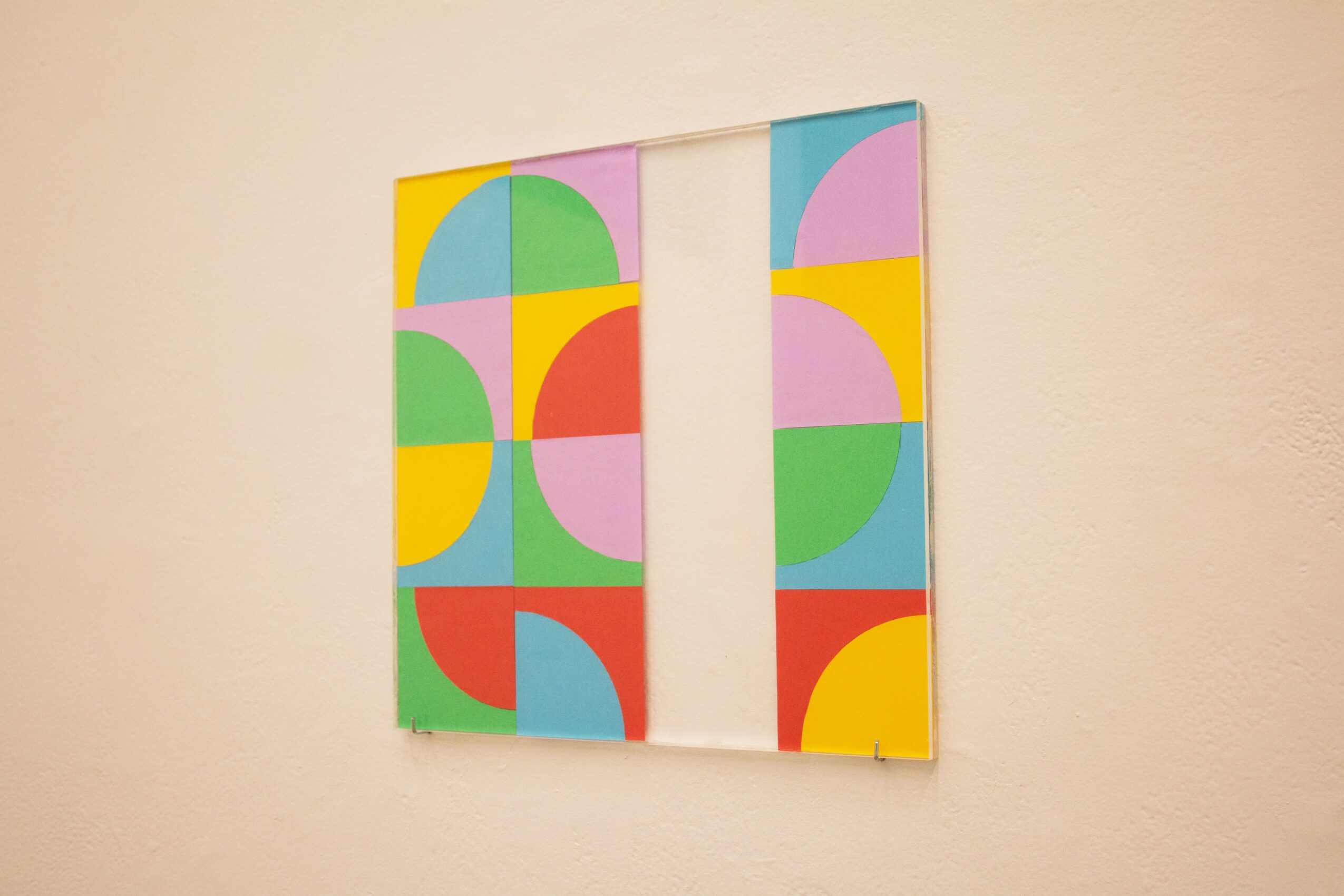 Colorful geometric abstract artwork with various shapes and bright colors on a wall.