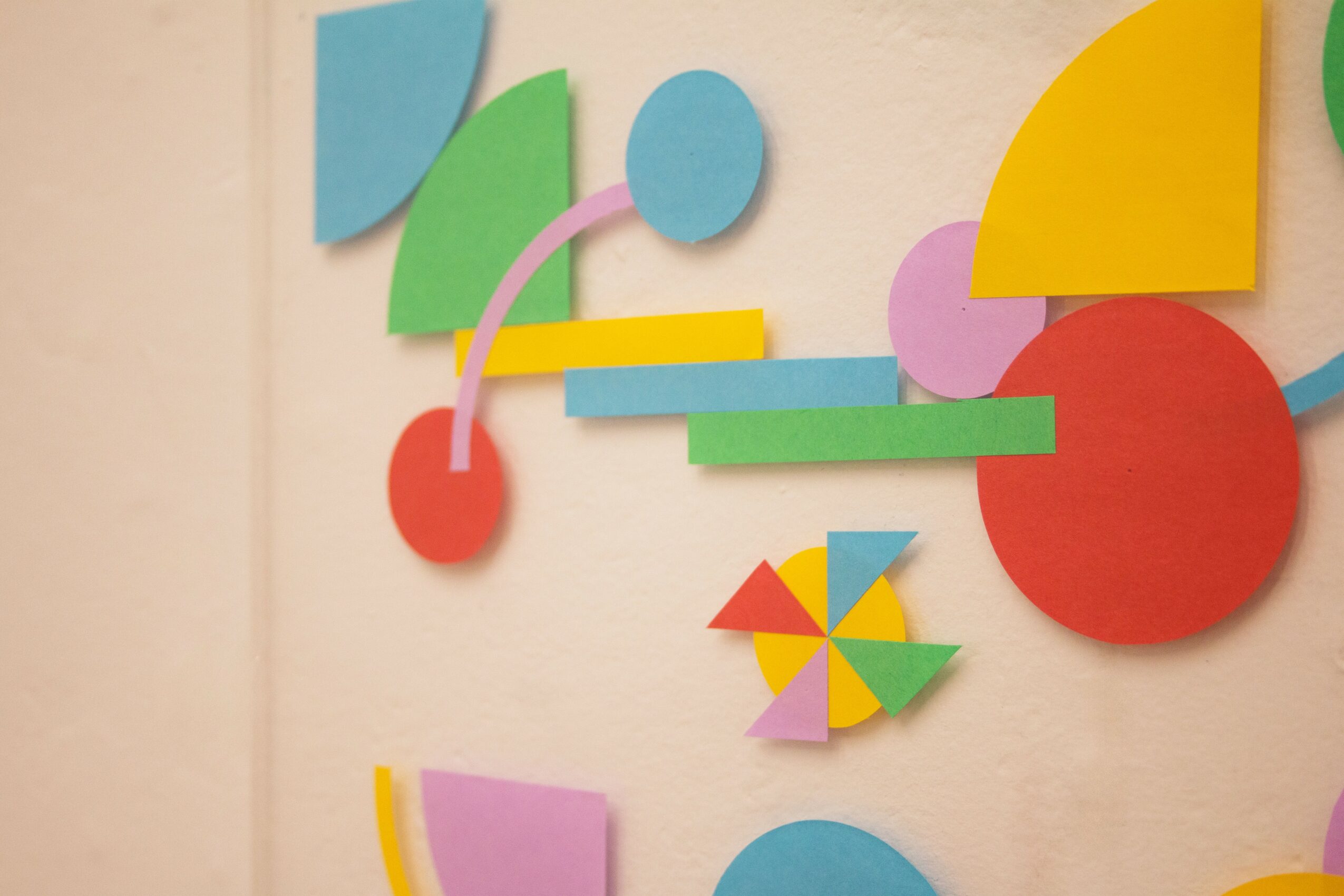 Colorful geometric shapes arranged on a wall, including circles, semi-circles, rectangles, and a pinwheel-like shape.