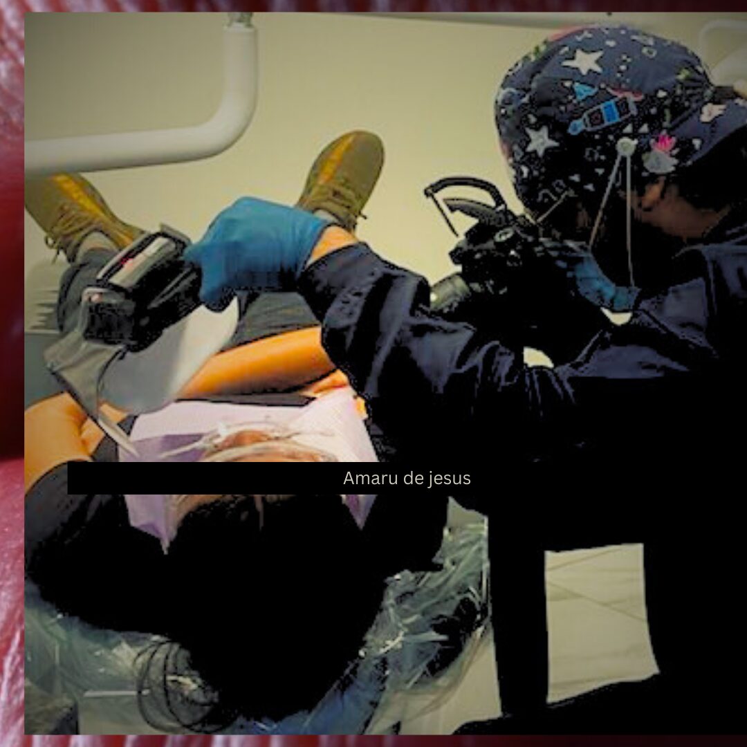 Medical professional attending to a patient lying on a dental chair, with equipment and a person wearing a cap nearby.
