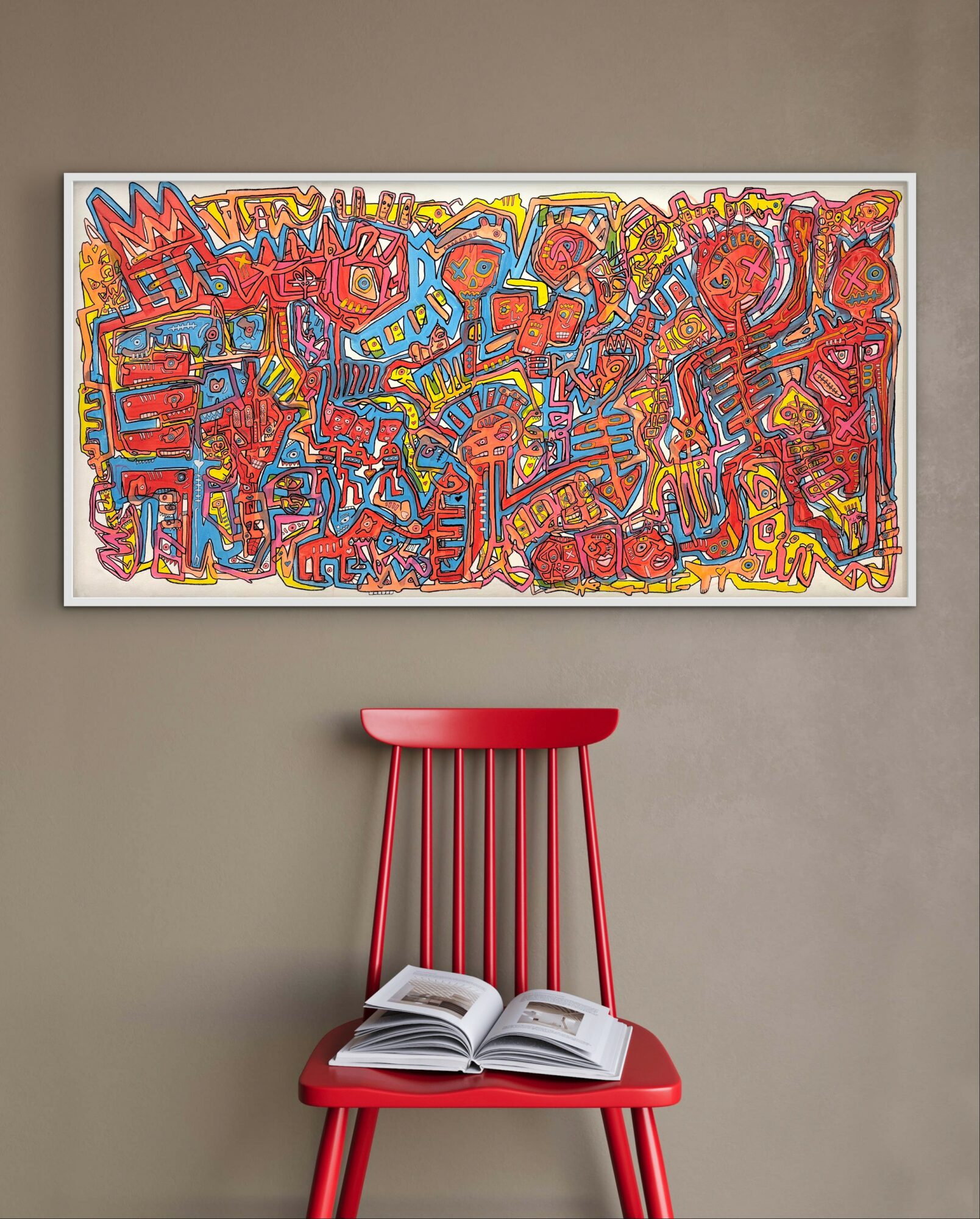 Colorful abstract painting with various shapes and patterns hangs on a gray wall above a red chair with an open book.