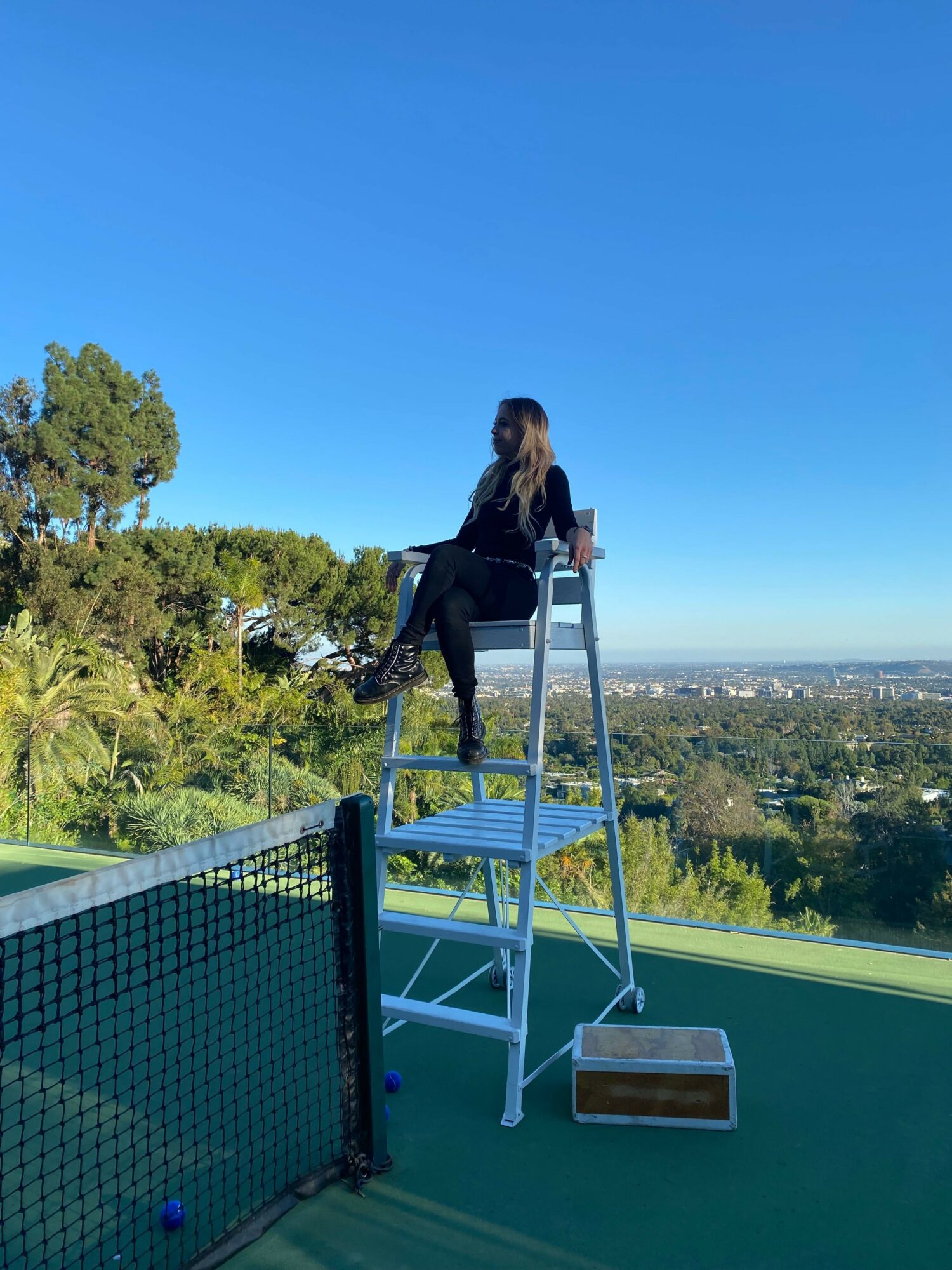Person standing on a ladder on a rooftop with a city view in the background.