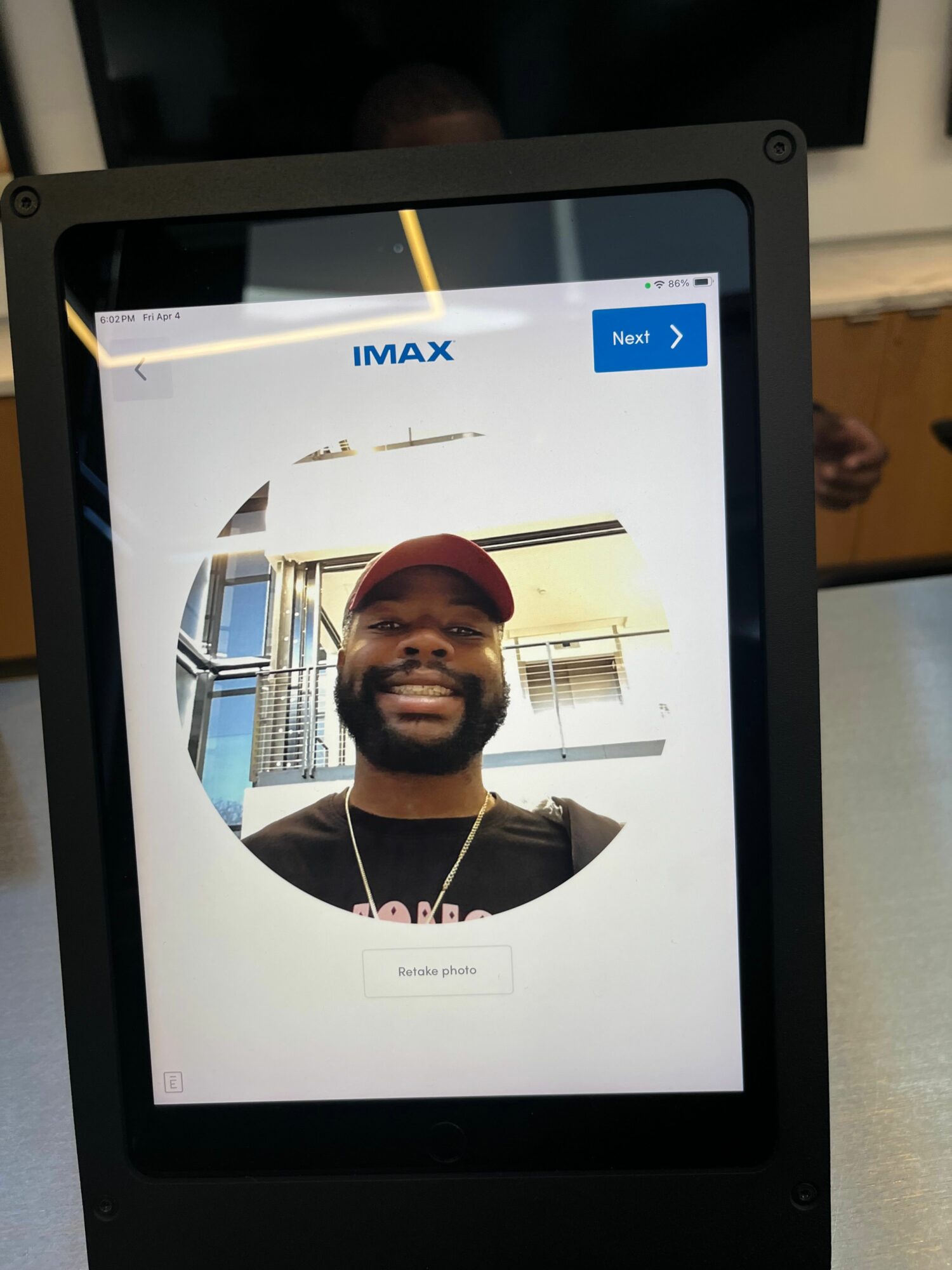 Tablet screen showing a smiling person wearing a red cap and black shirt, with a circular crop around their face.