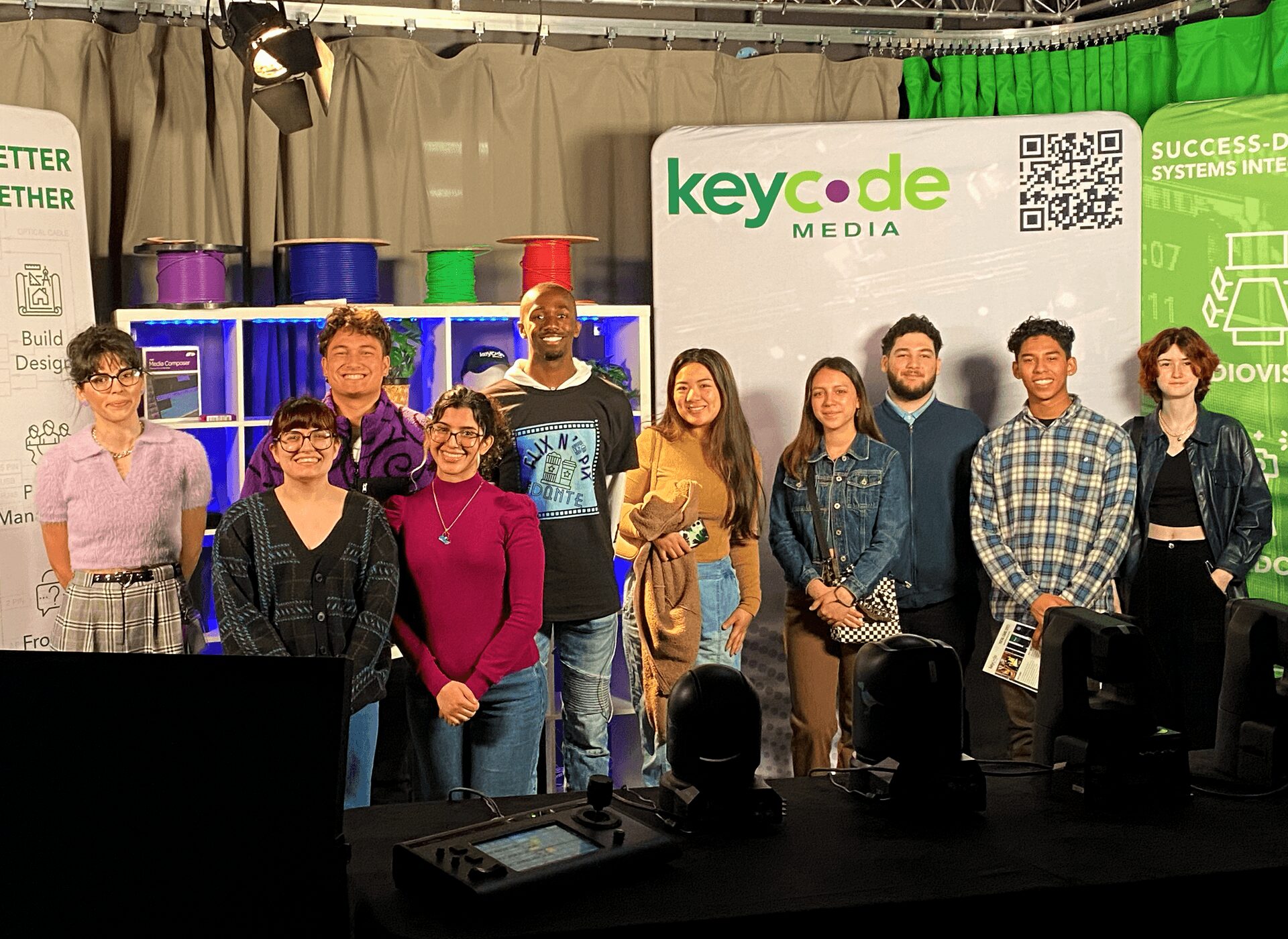 Group of ten people standing on stage in front of a Keycode Media banner, smiling for photo.