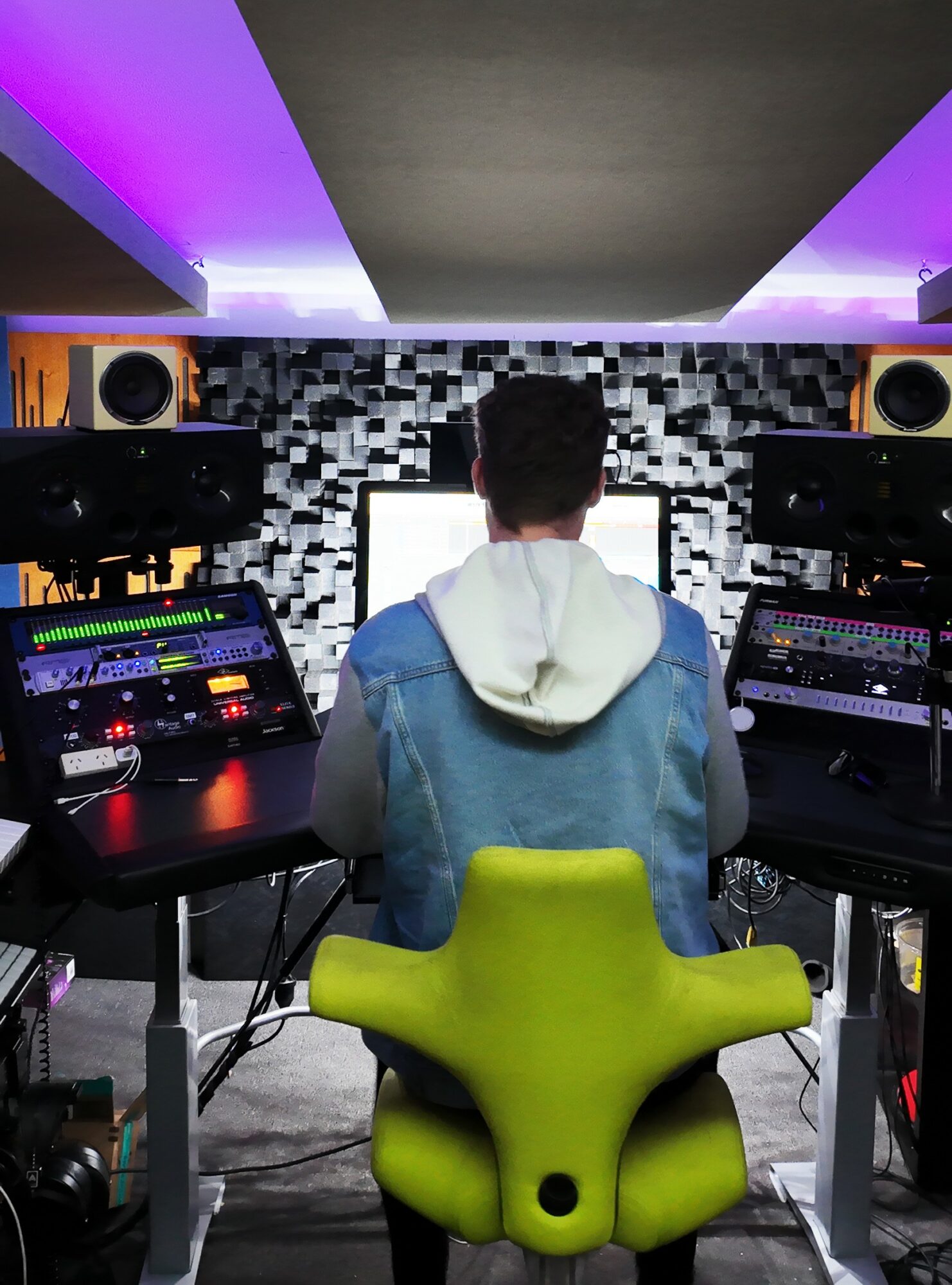 Person with back facing computer monitors in a music studio with black and white patterned wall.