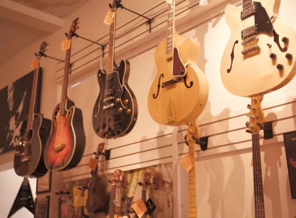 Six guitars hanging on a wall in a music store, with various shapes and colors.