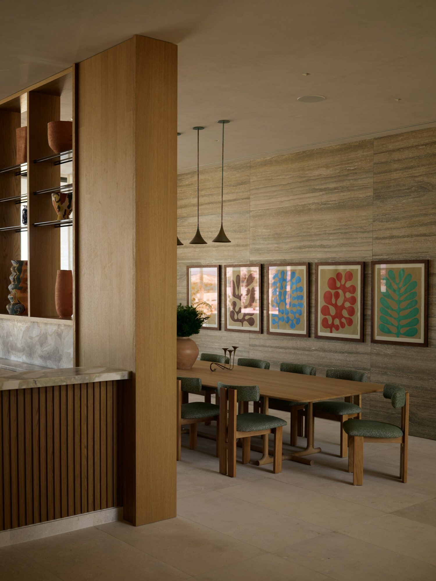 Dining area with wooden table, chairs, framed artwork, and pendant lights, in a modern interior setting.