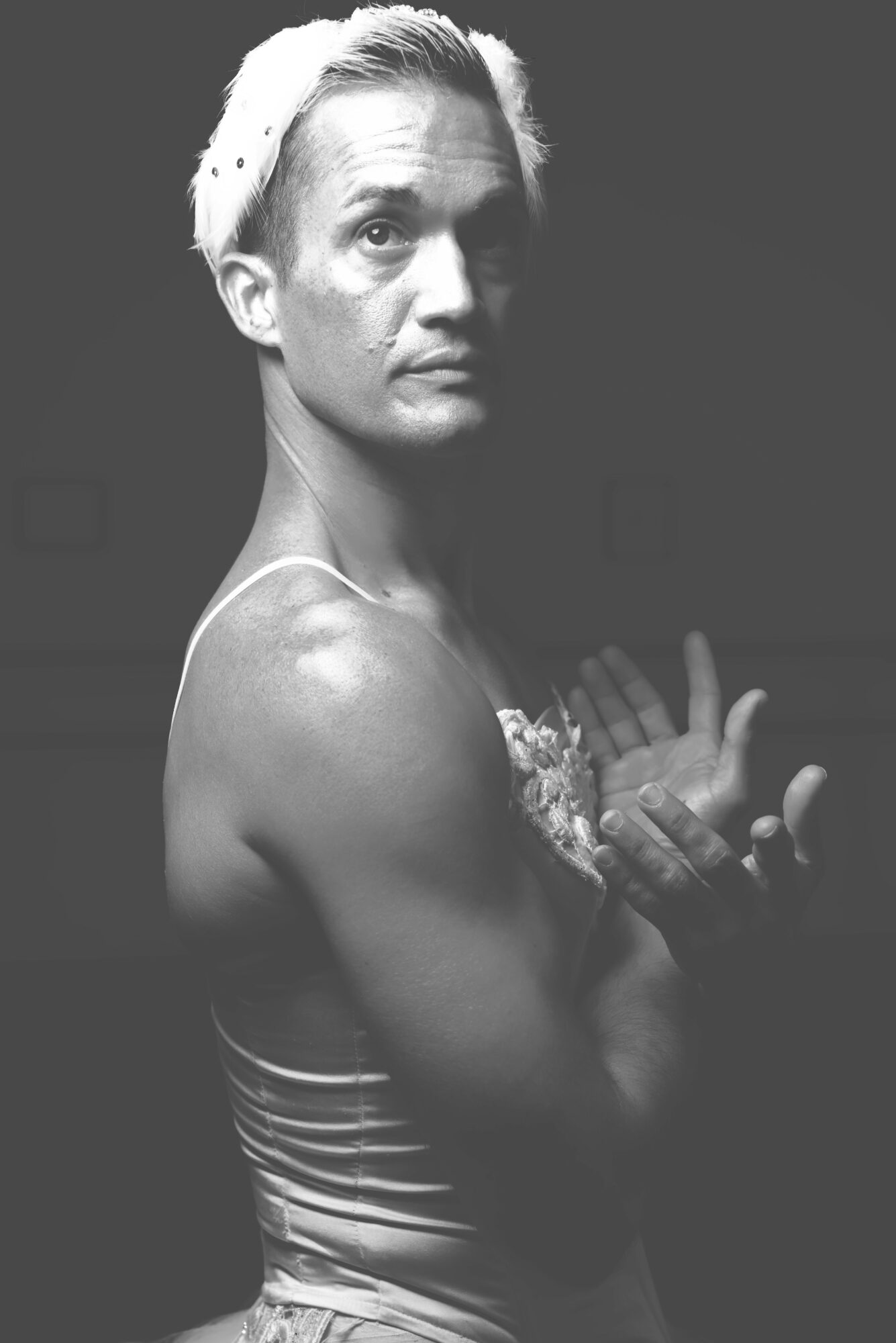 Black and white portrait of a person with short, light-colored hair, looking at the camera with crossed arms.