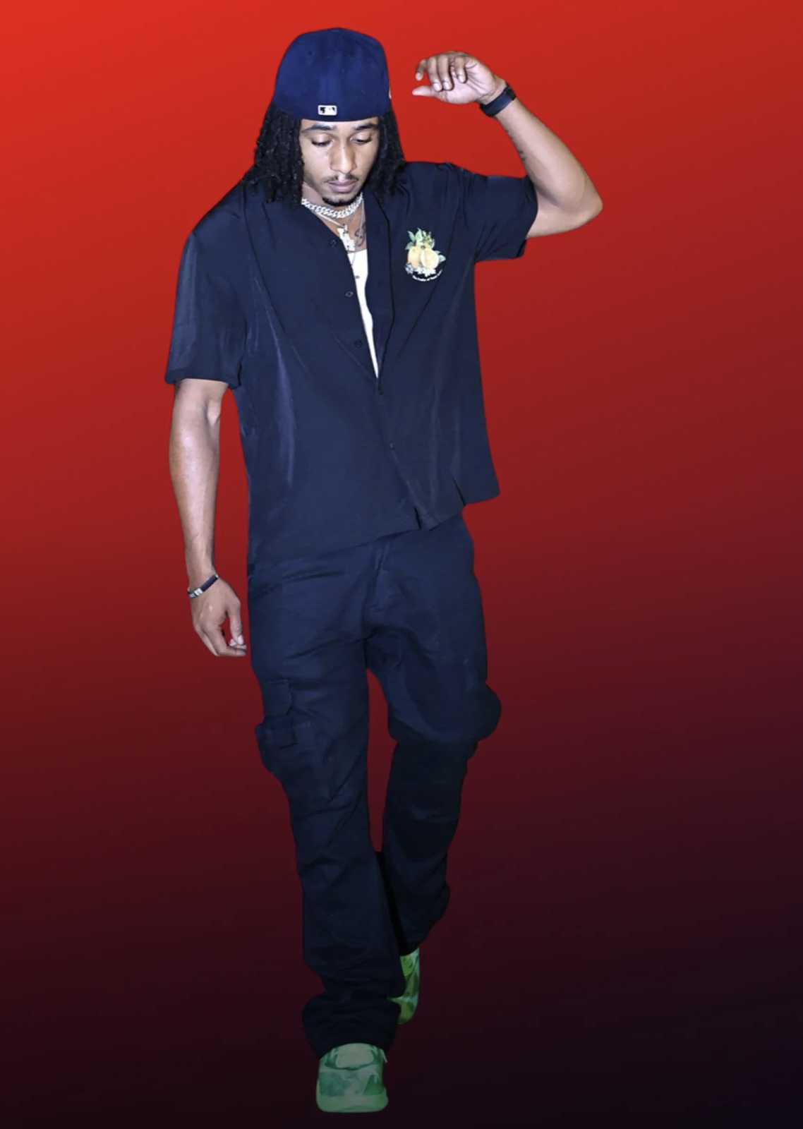 Person with long hair, wearing a beanie, black shirt, and pants, standing against a red background.