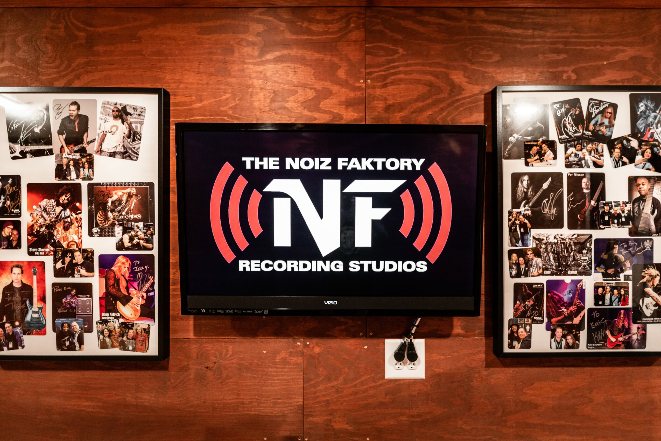 Wall with framed photos on each side of a central screen displaying 'The Noiz Faktory' logo.