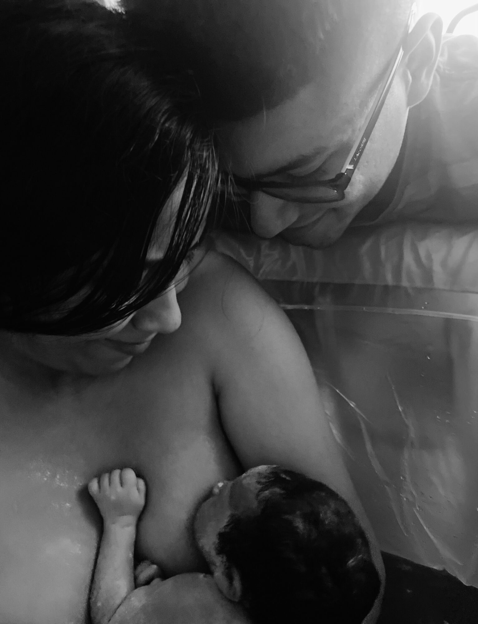 Adult and child lying close together, with the child breastfeeding, in a black and white photo.