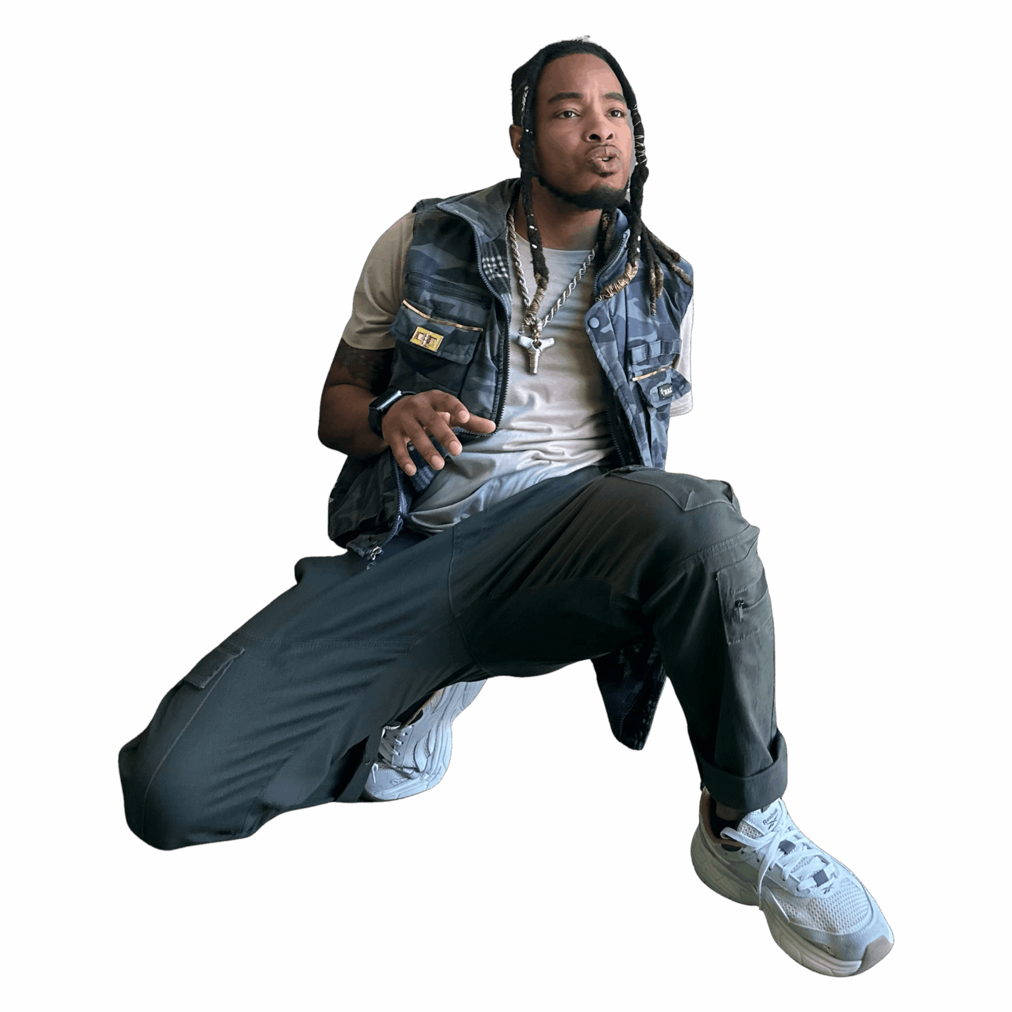 Person with long hair, wearing a vest, sitting with one knee up, against a black background.
