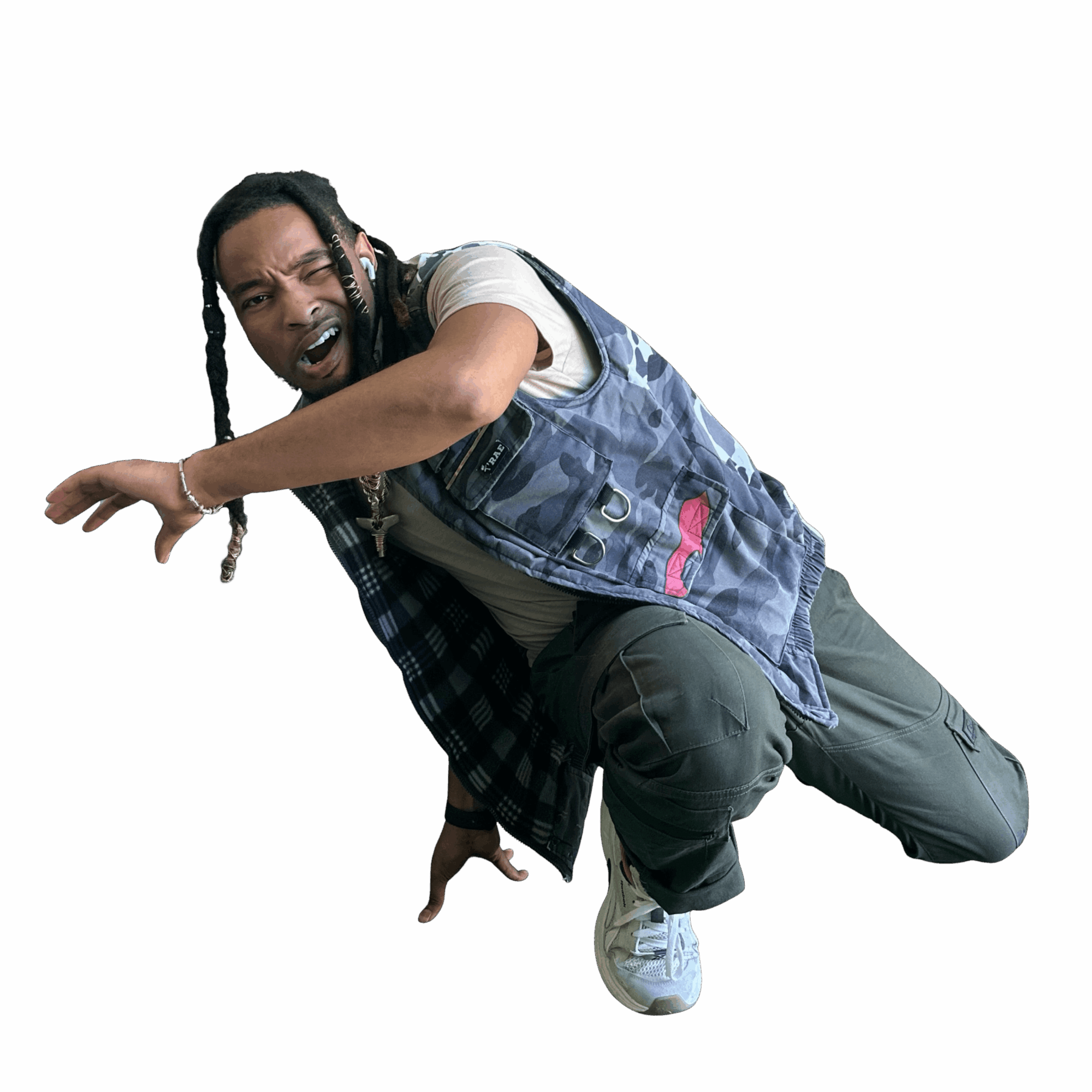Person crouching with an expressive face, wearing a denim vest, plaid shirt, and sneakers, against a black background.