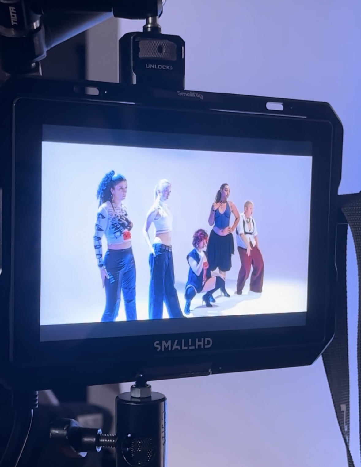 Monitor displaying five people standing and posing against a plain background.