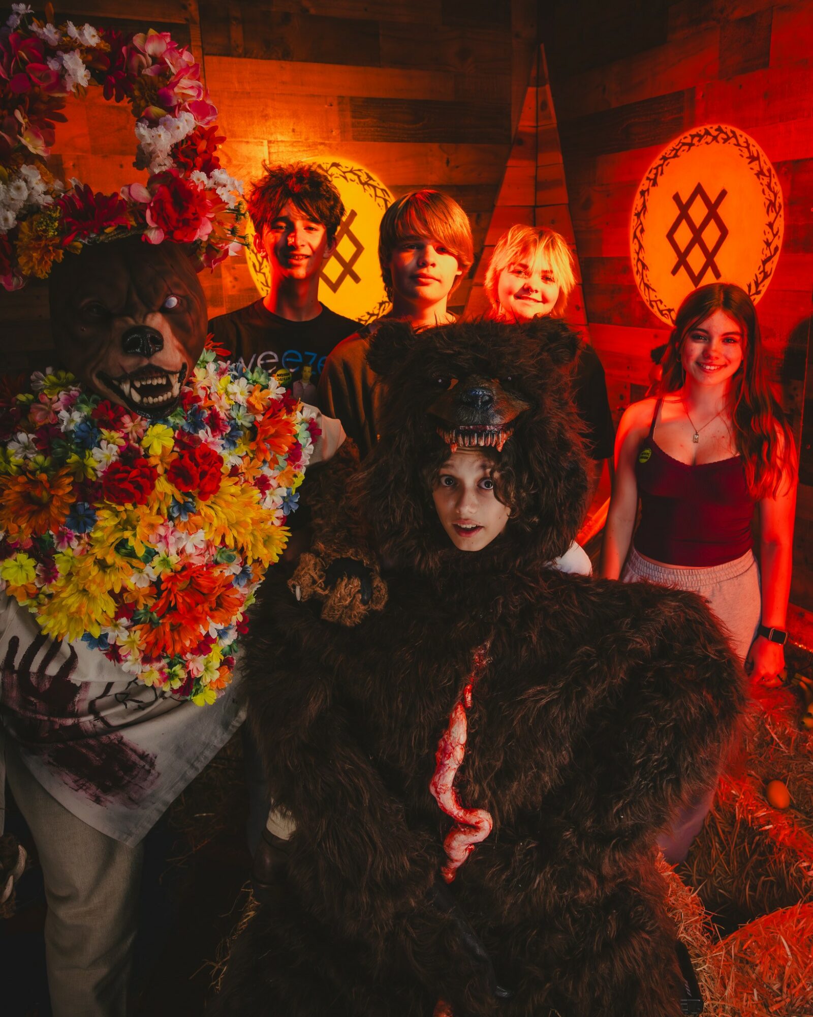 Group of five people in costumes, one dressed as a black furry creature, in a decorated room with warm lighting.