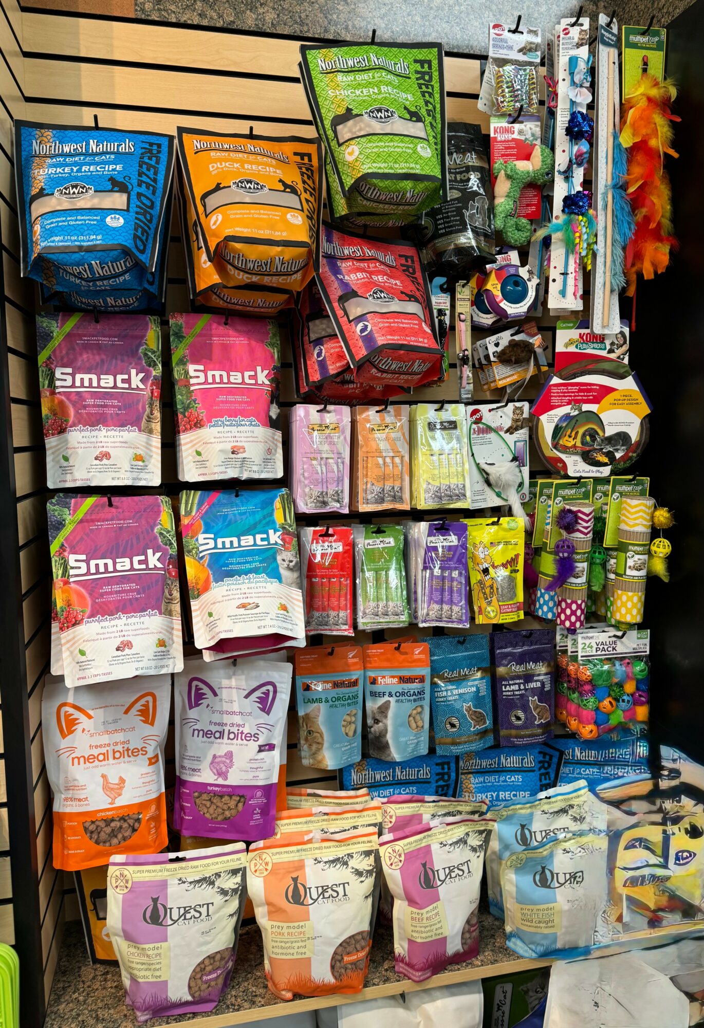 Display of various pet supplies including bags of treats, toys, and grooming items on shelves.