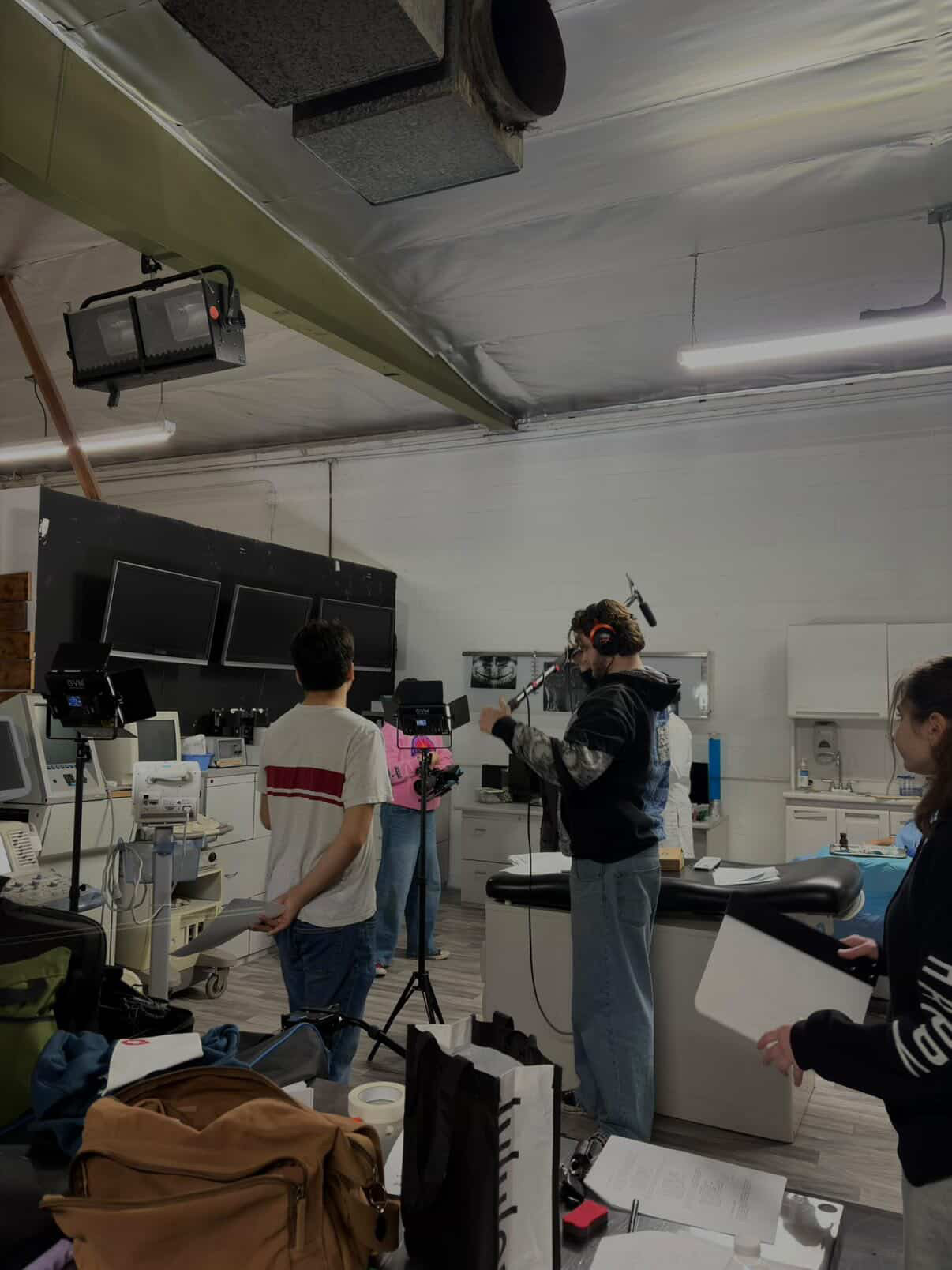 Laboratory with people working around equipment and monitors, white walls, and ceiling lights.