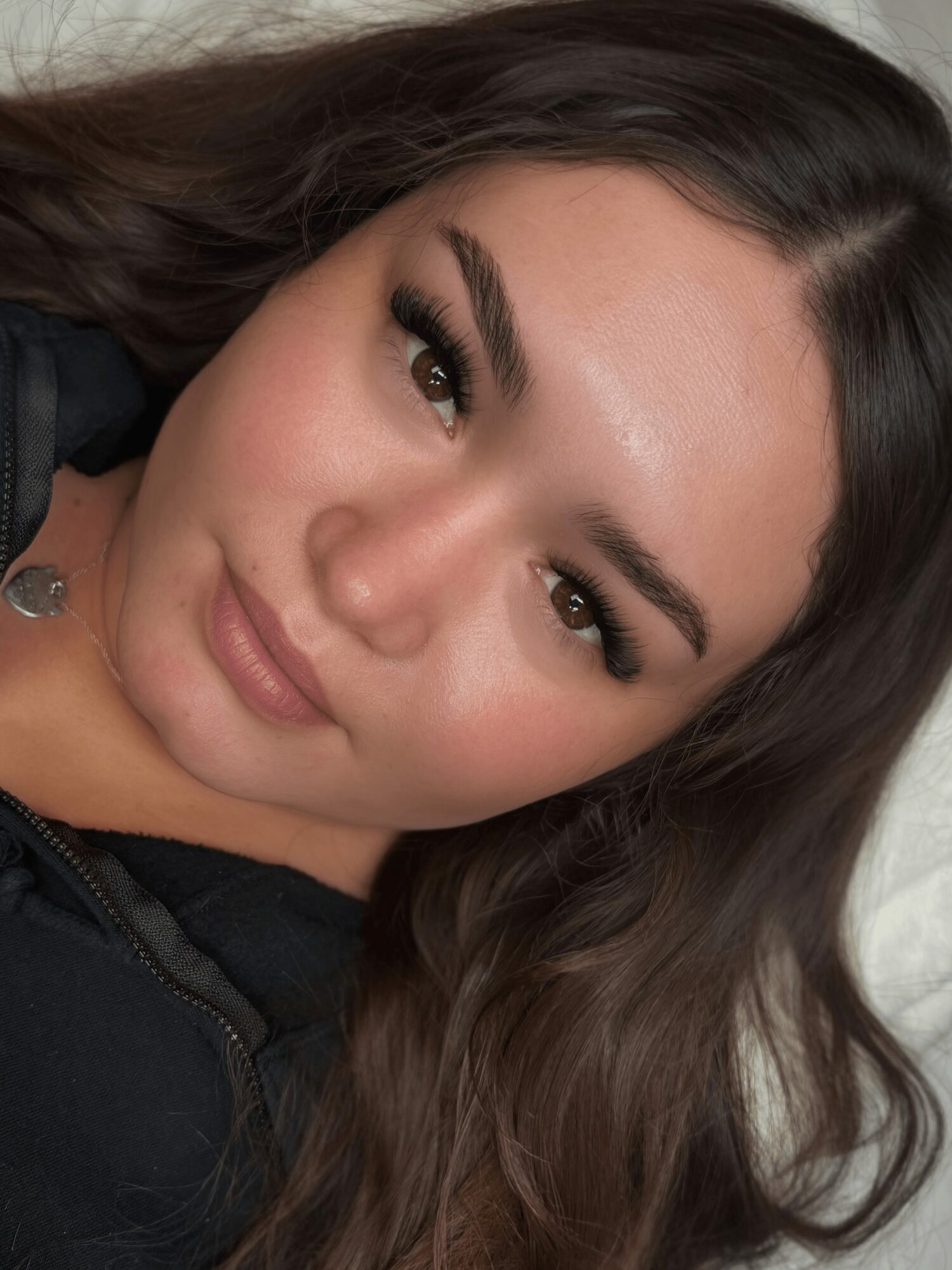 Close-up of a woman with long dark hair, makeup, and a neutral expression.