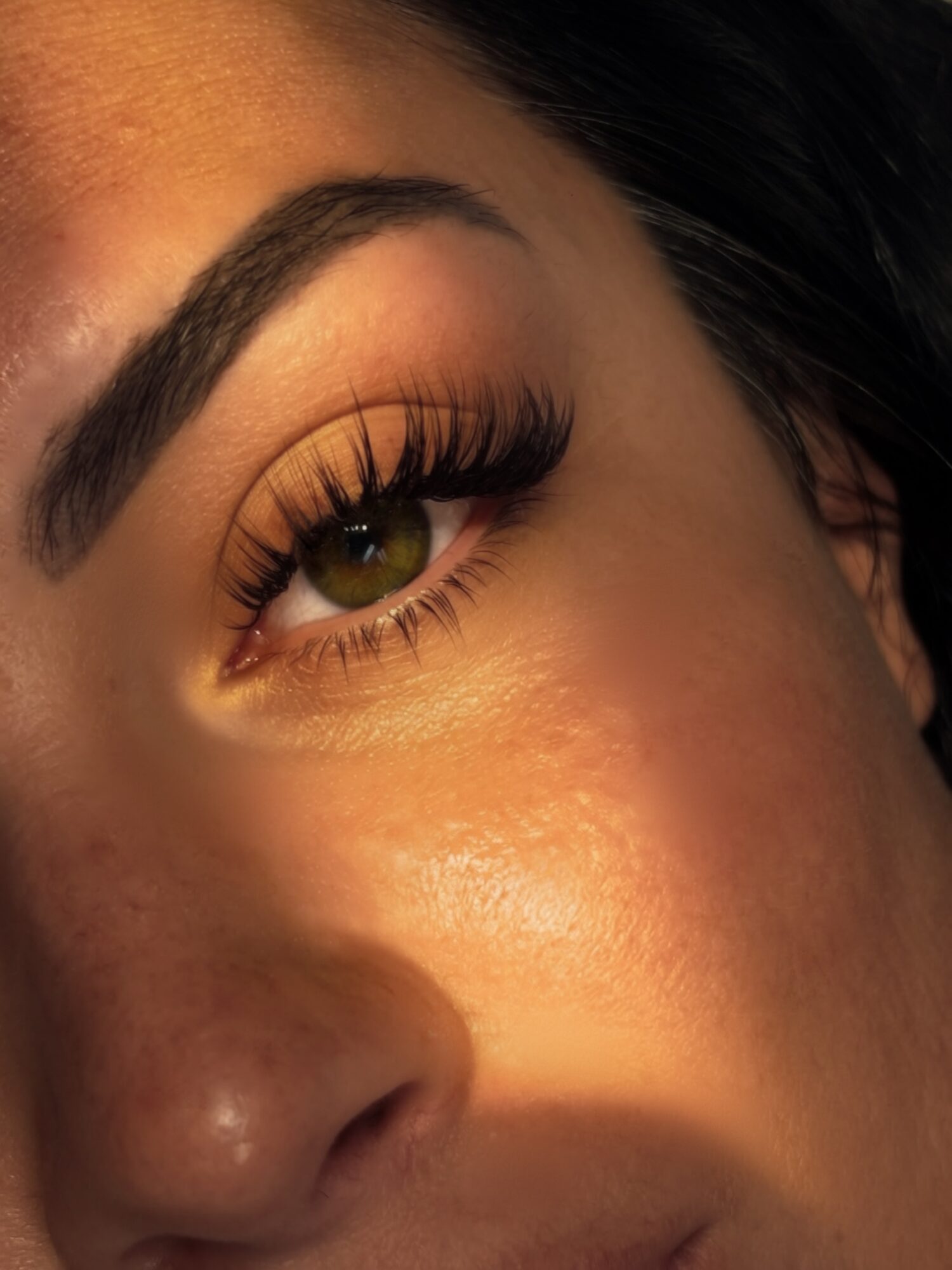 Close-up of a person's eye with makeup, long eyelashes, and well-defined eyebrow.