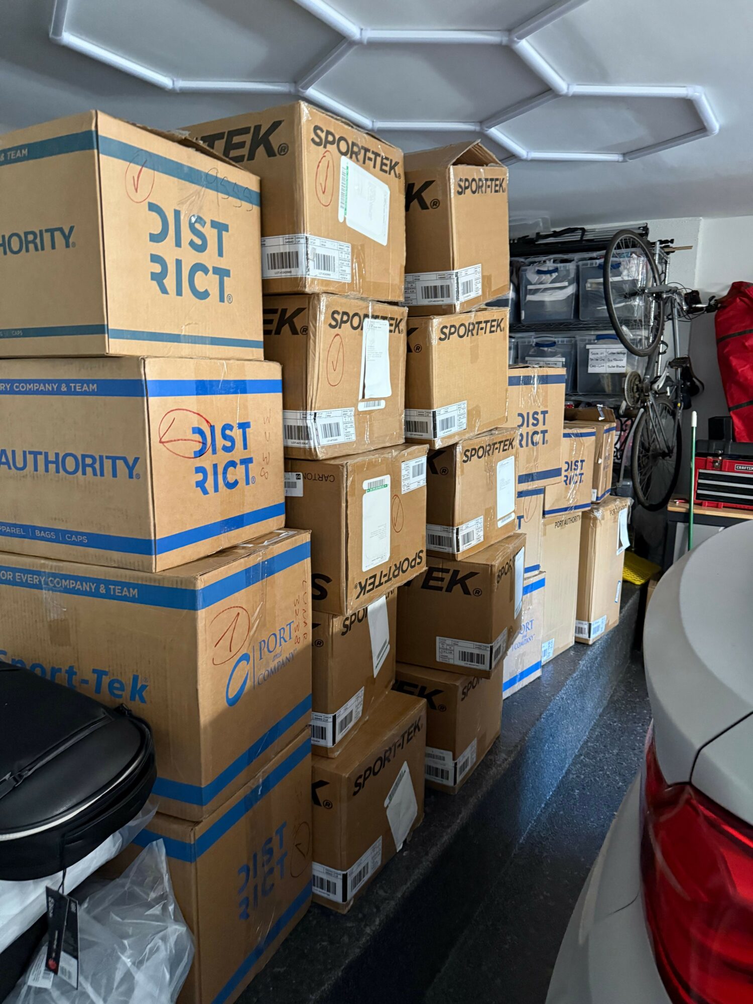 Stacked boxes labeled 'SPORTTEK' and 'DISTRICT' in a room with a bicycle and other equipment.