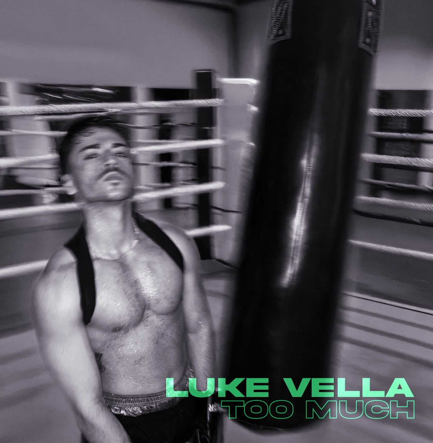 Young male boxer in a gym, shirtless, with a backpack, leaning against a punching bag, with boxing ring in background.
