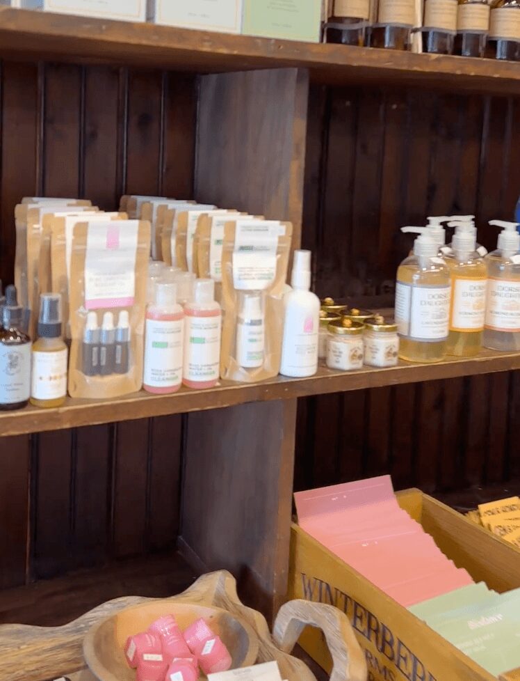 Shelves with various bottles, jars, and packages, including hand sanitizer bottles and small containers, in a store setting.