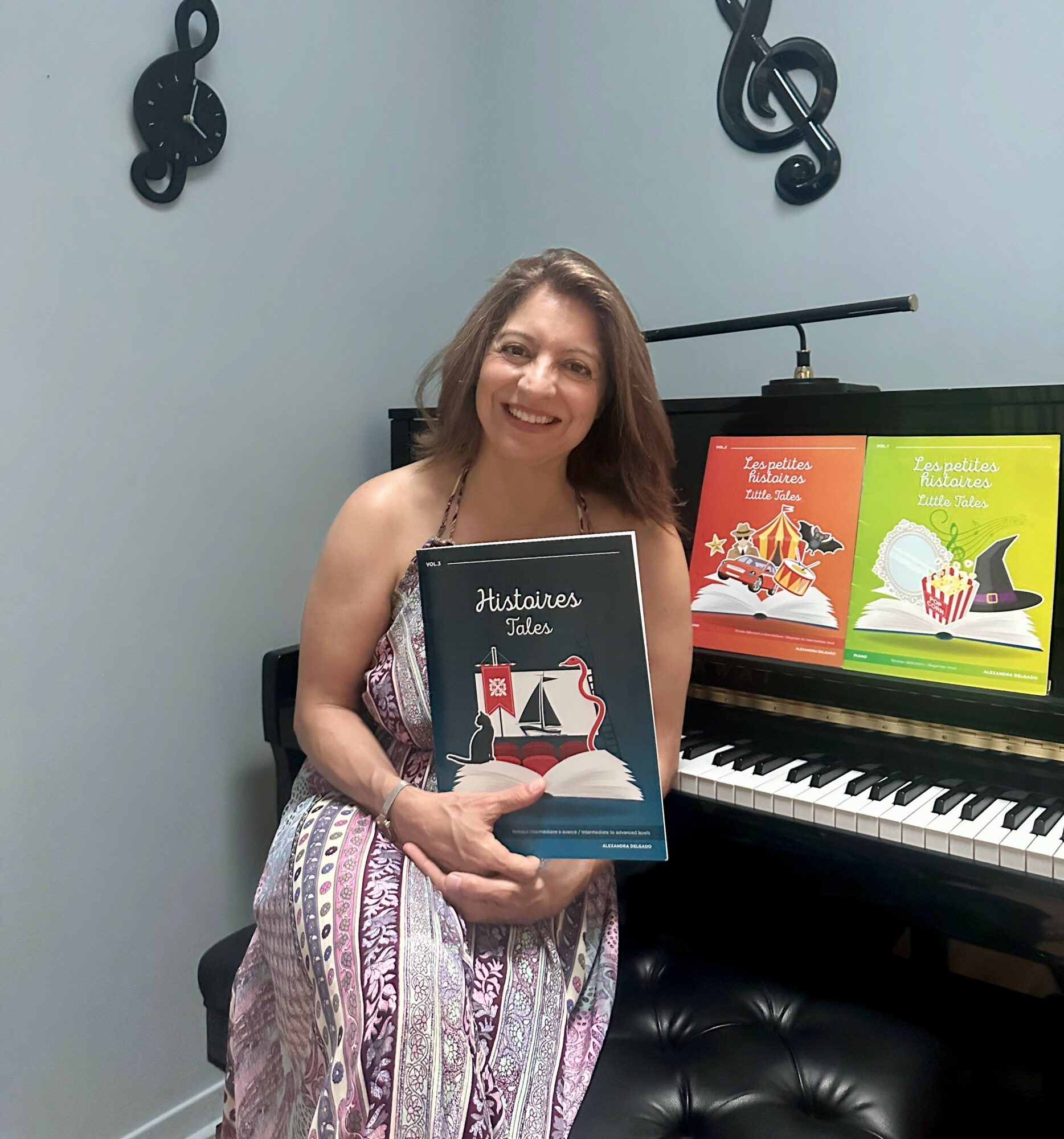 Woman sitting by piano holding a book, smiling, with musical note decorations on wall behind her.