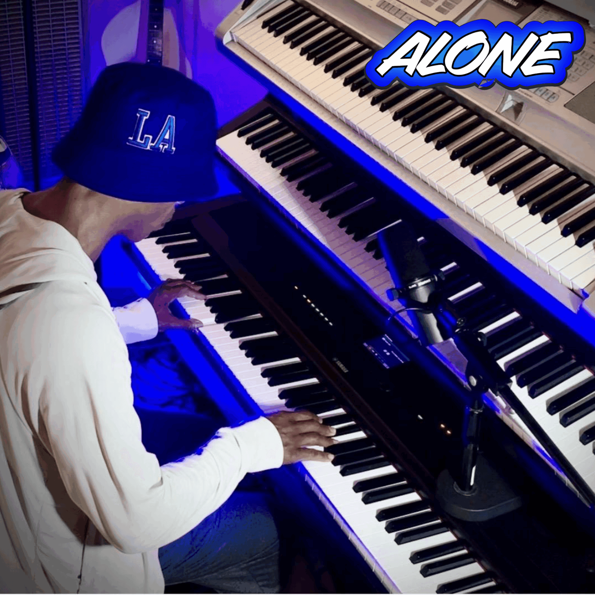 Person playing a keyboard with multiple pianos, wearing a blue cap with 'L.A.' and a white hoodie, in a music studio.