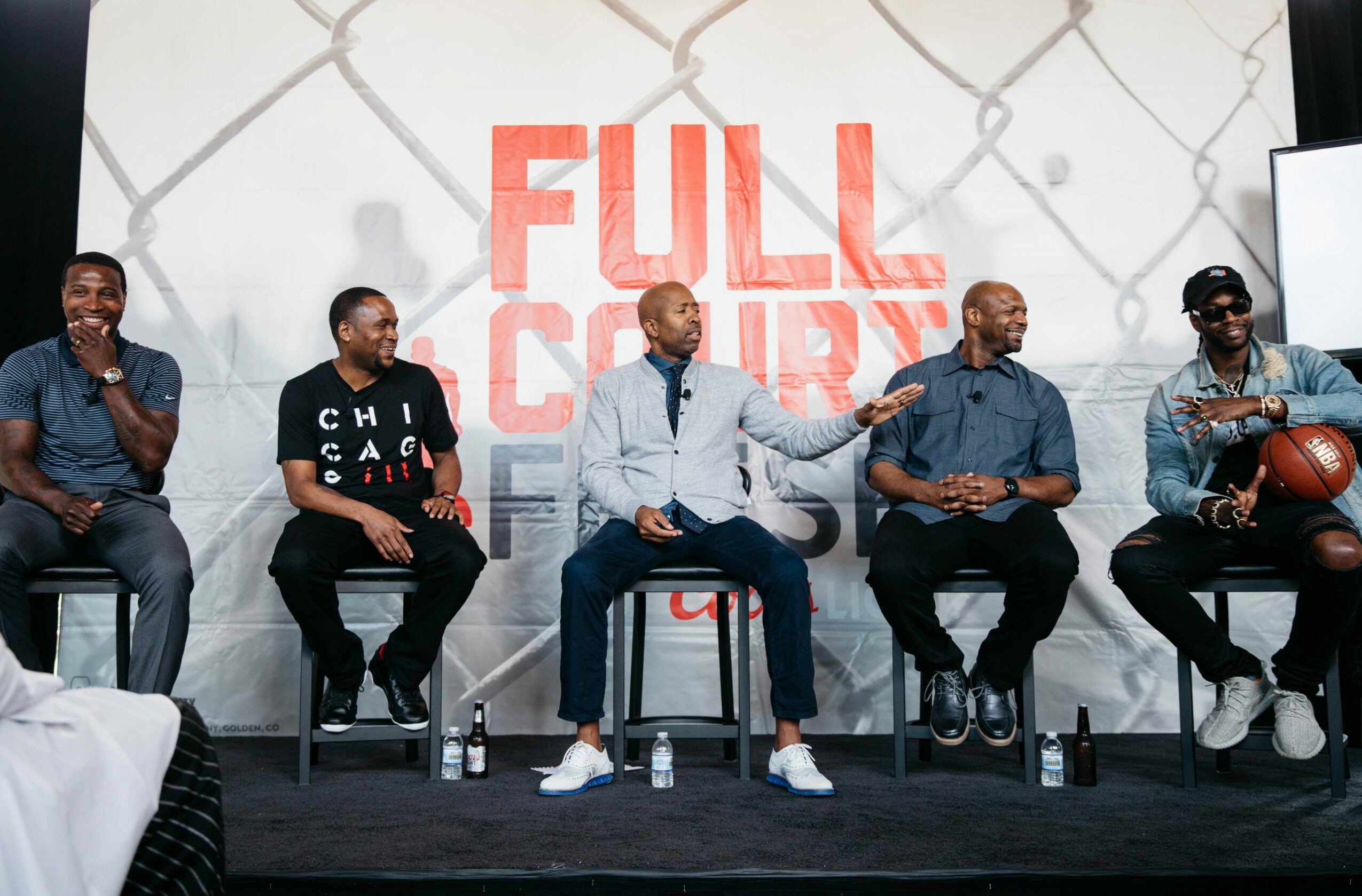 Five men sit on stools in front of a chain-link fence background with large red text reading 'FULL COURT'.