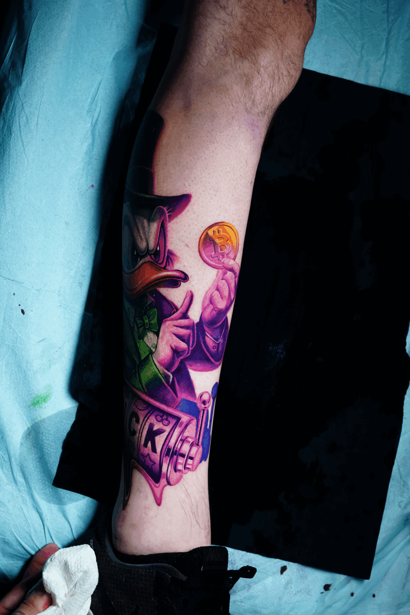Colorful tattoo of a woman with a hat and a snake on a person's lower leg, with vibrant purple, pink, and green hues.