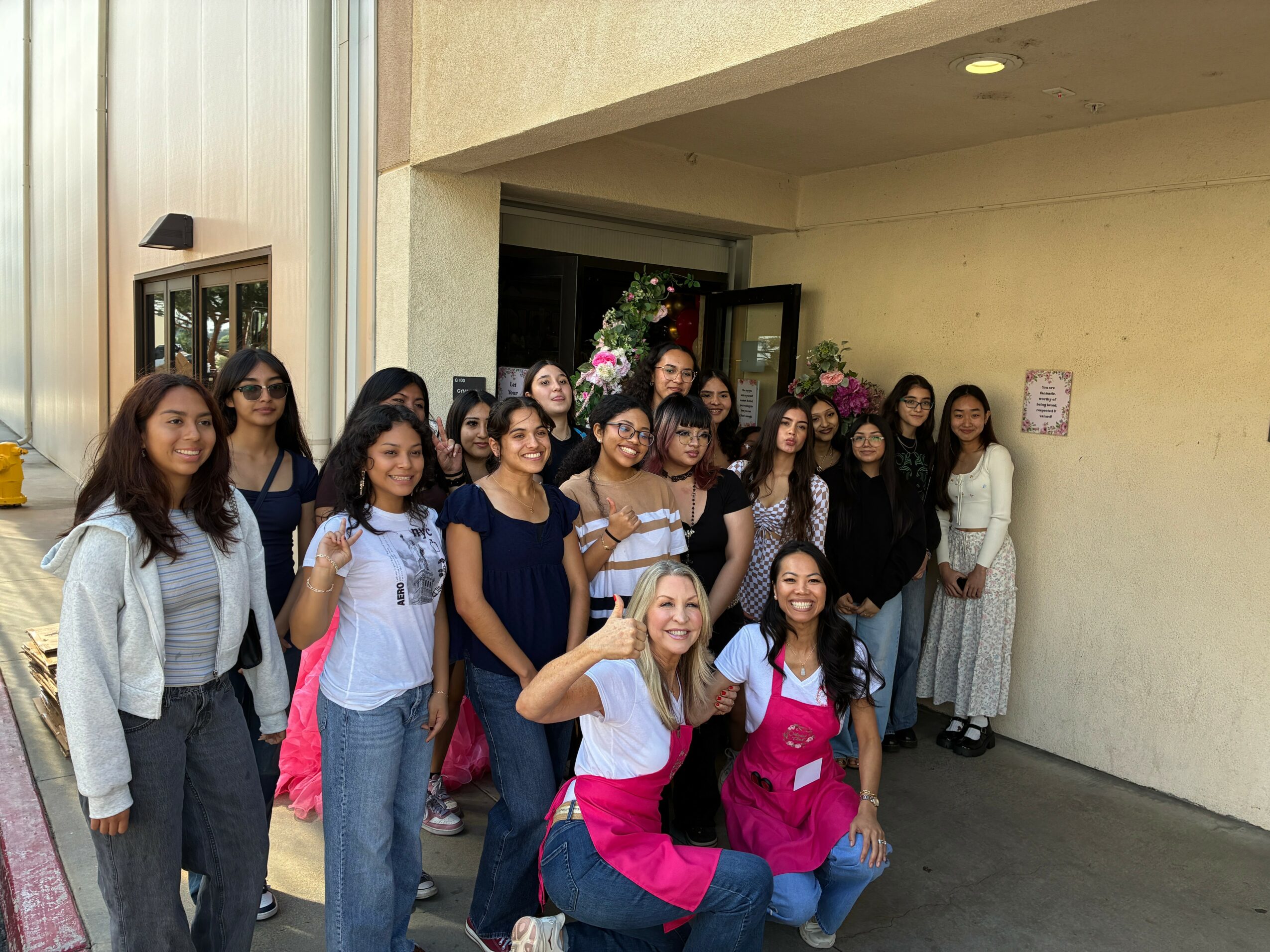 Group of women standing outside a building, some smiling and posing for the photo.