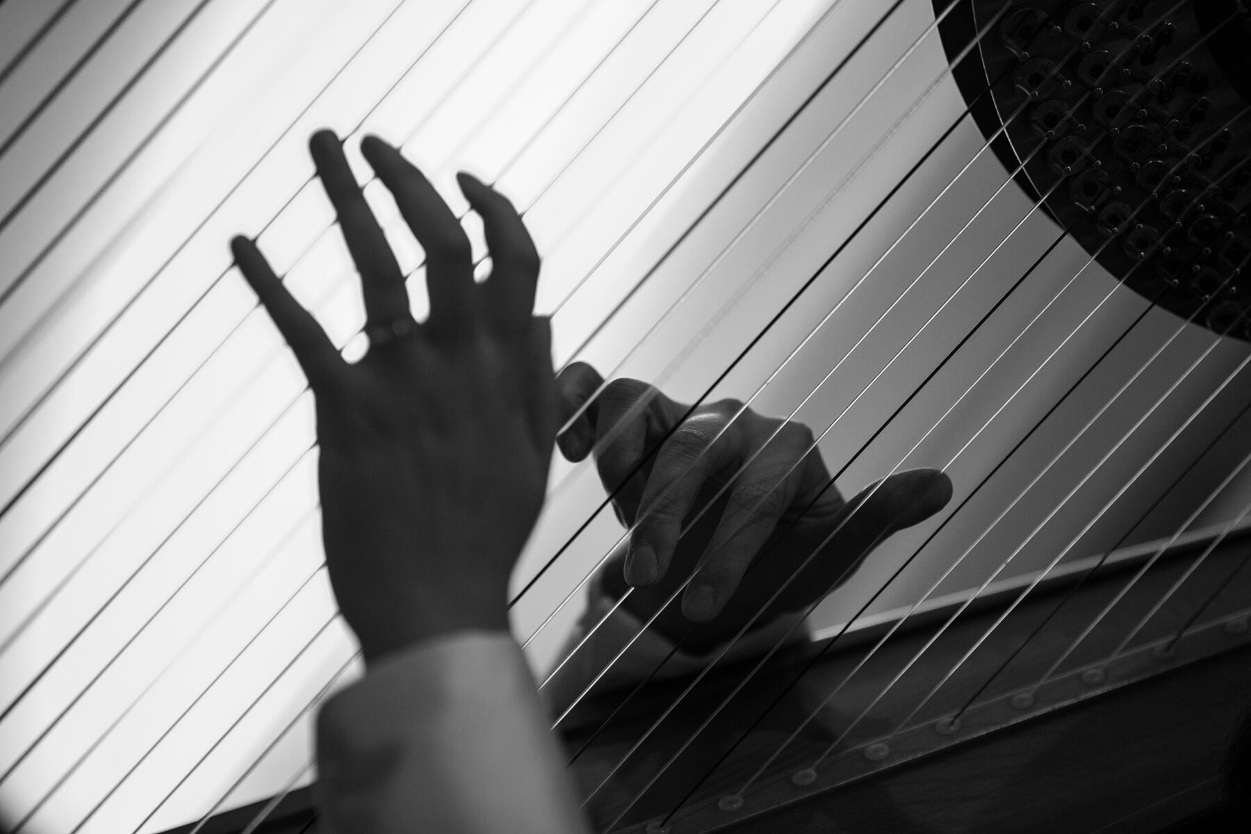 Hand reaching out and touching a glass surface with horizontal lines, with a dark circular object in the background.