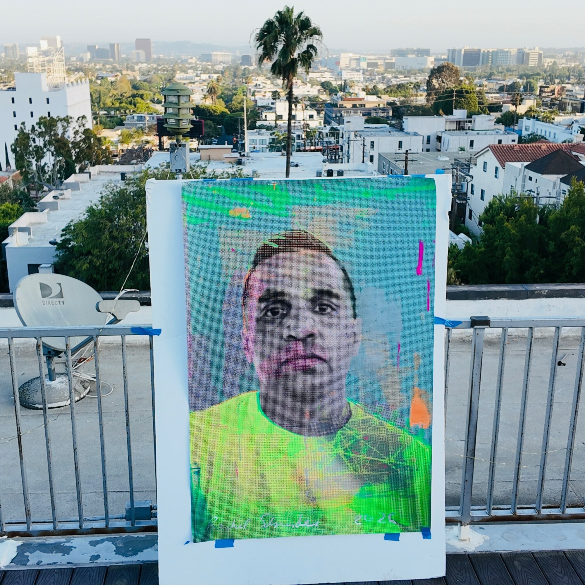 Large digital screen displaying a person's face with a cityscape background, rooftop setting, and railings.