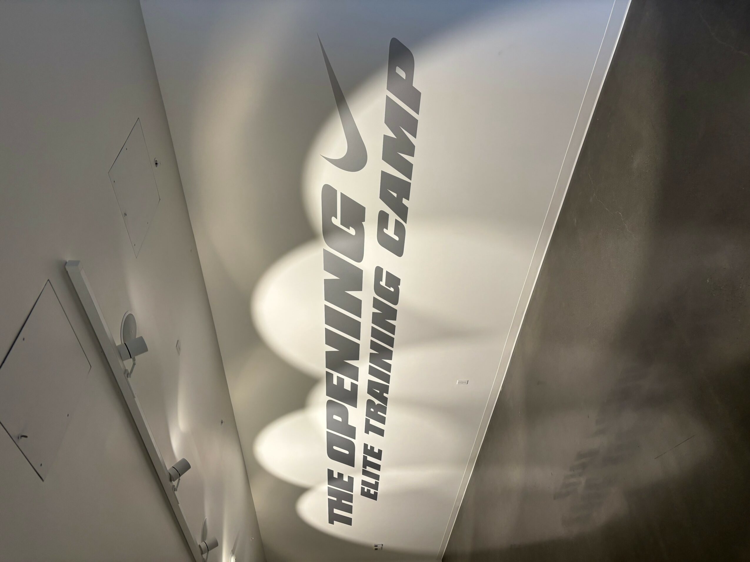 Vertical sign with text and Nike logo, reading 'The Opening, The Training Camp'.