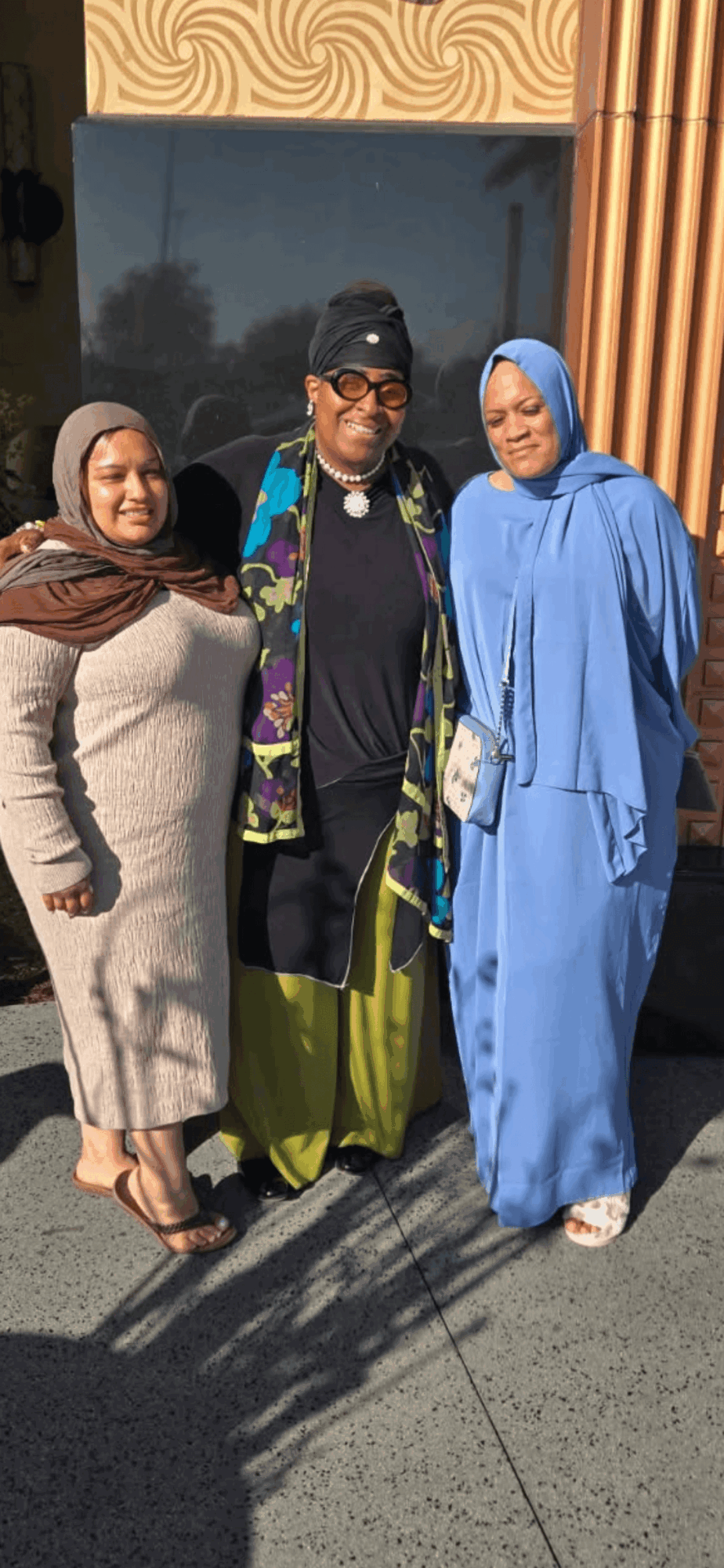 Three people standing outdoors, two women and one man, smiling and posing for the photo.