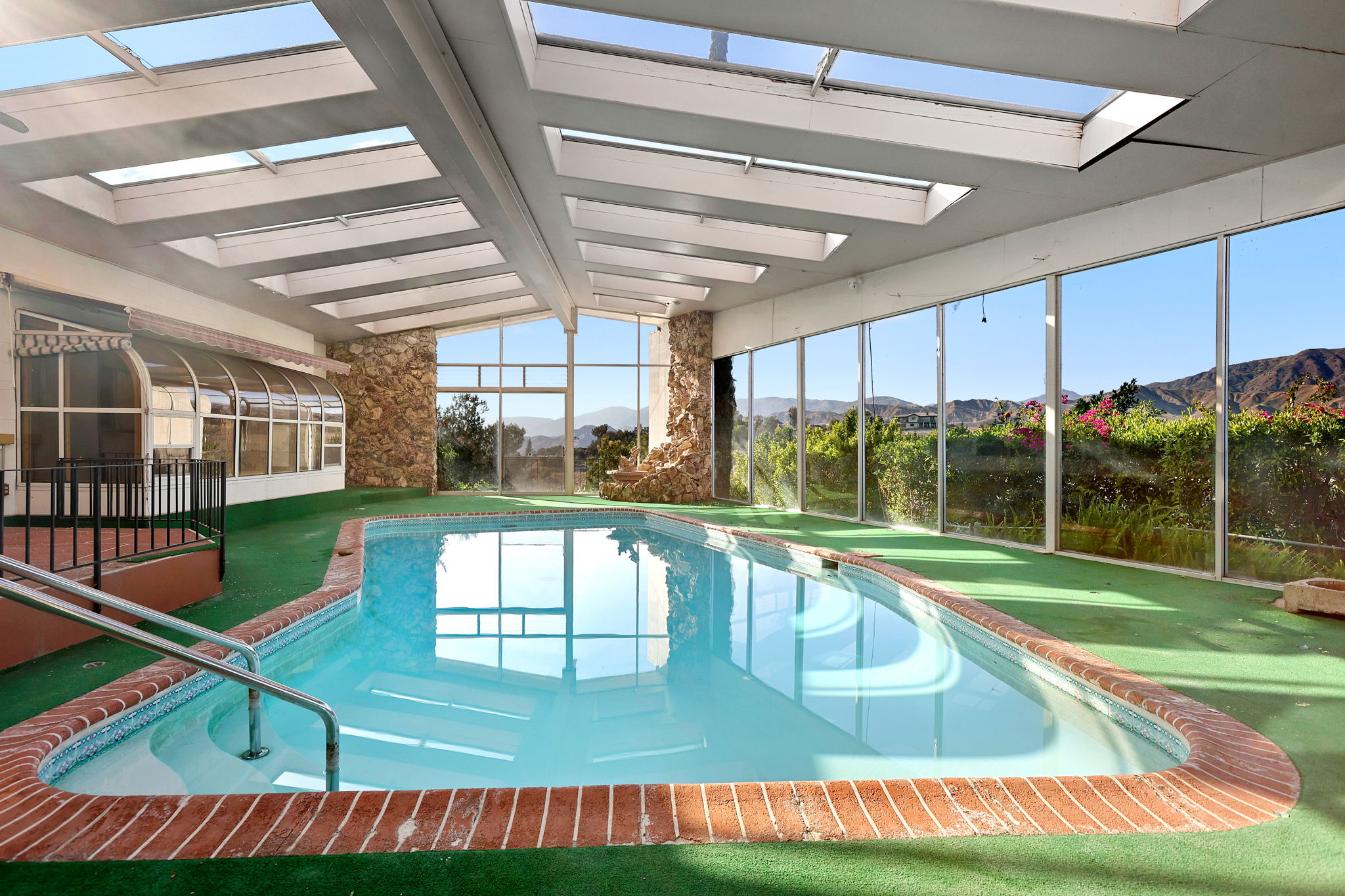 Indoor swimming pool with large windows, skylights, and a view of mountains outside.