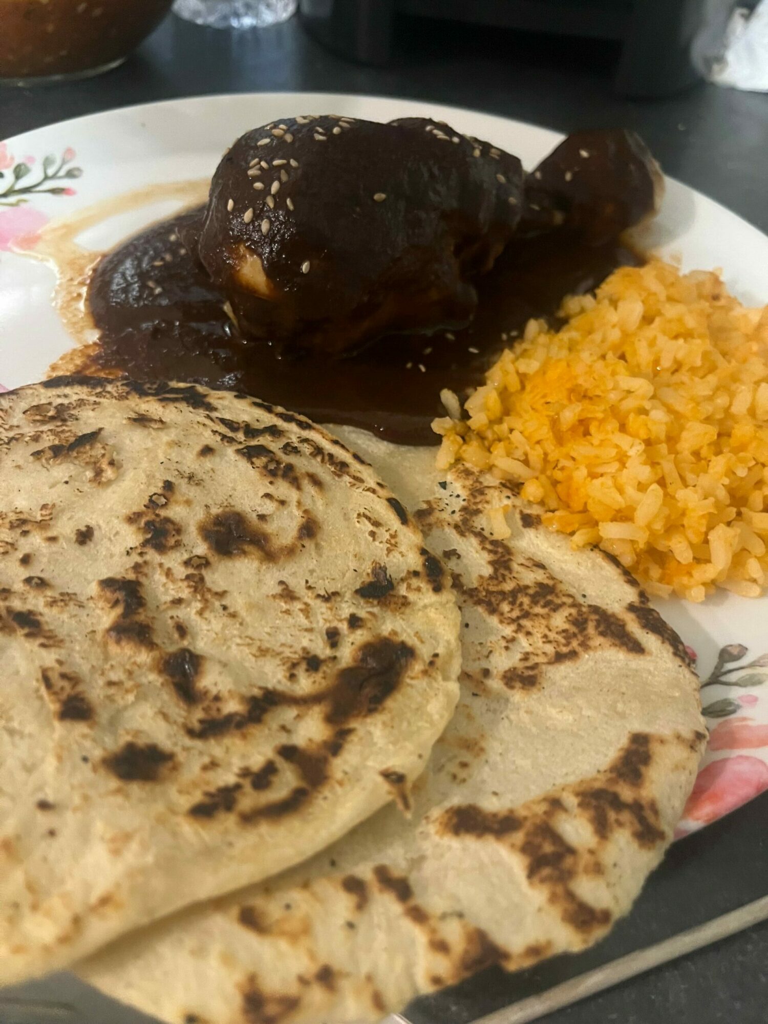 Three grilled tortillas, a serving of yellow rice, and a piece of meat with sauce on a plate.
