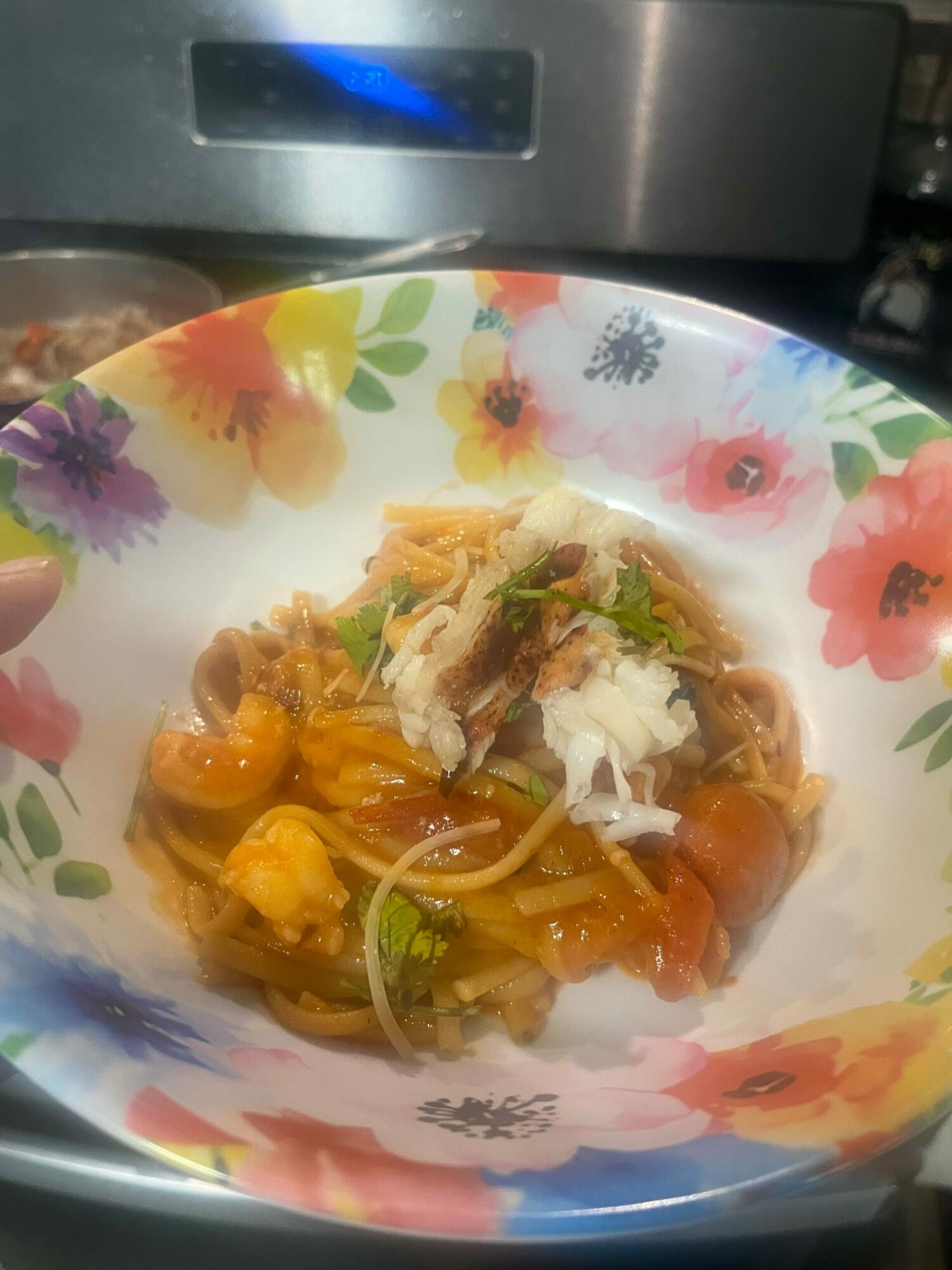 Plate with mixed vegetables and shredded meat on a floral plate, viewed from the side.